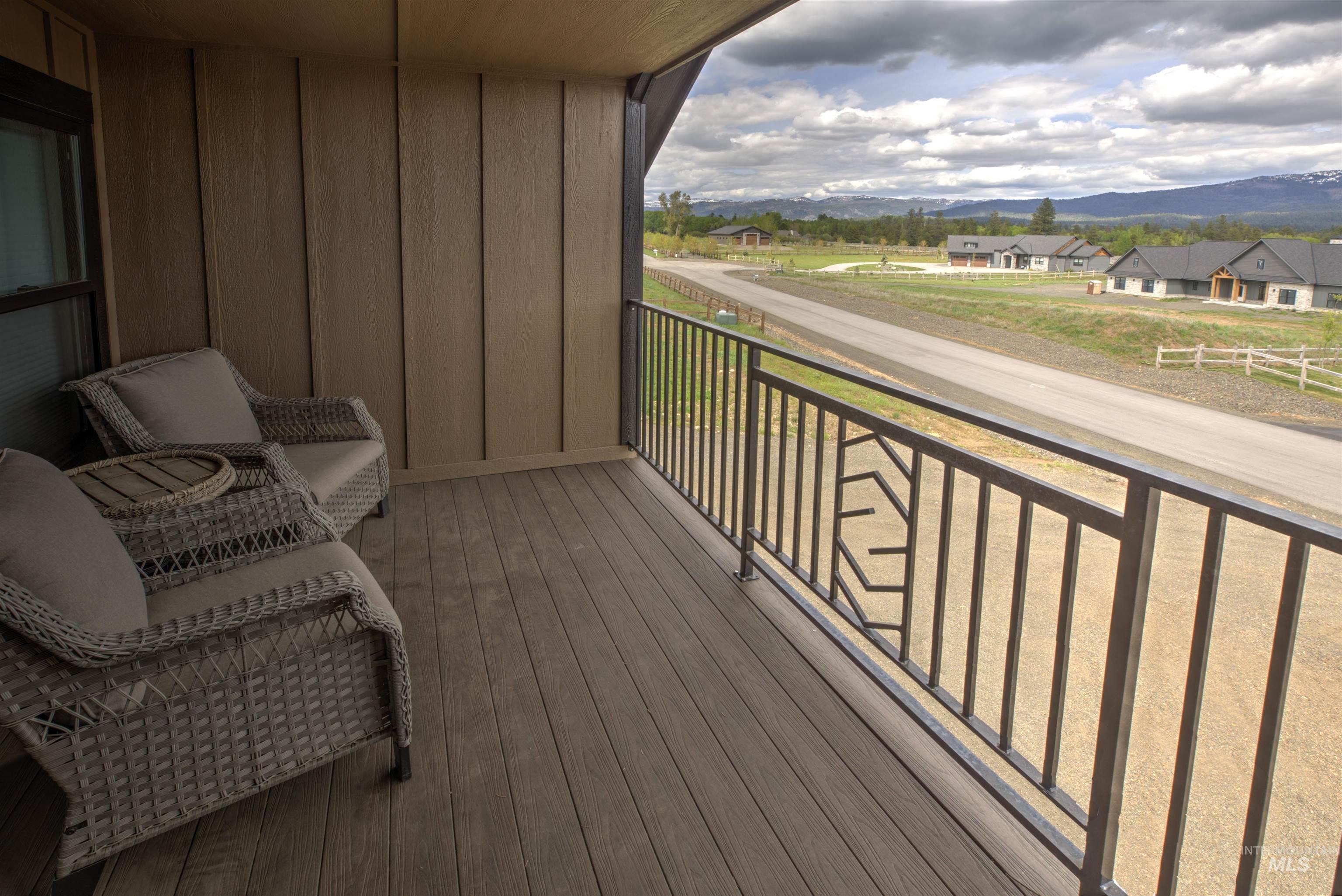 Covered outdoor balcony featuring composite decking and a black metal railing with a decorative geometric panel