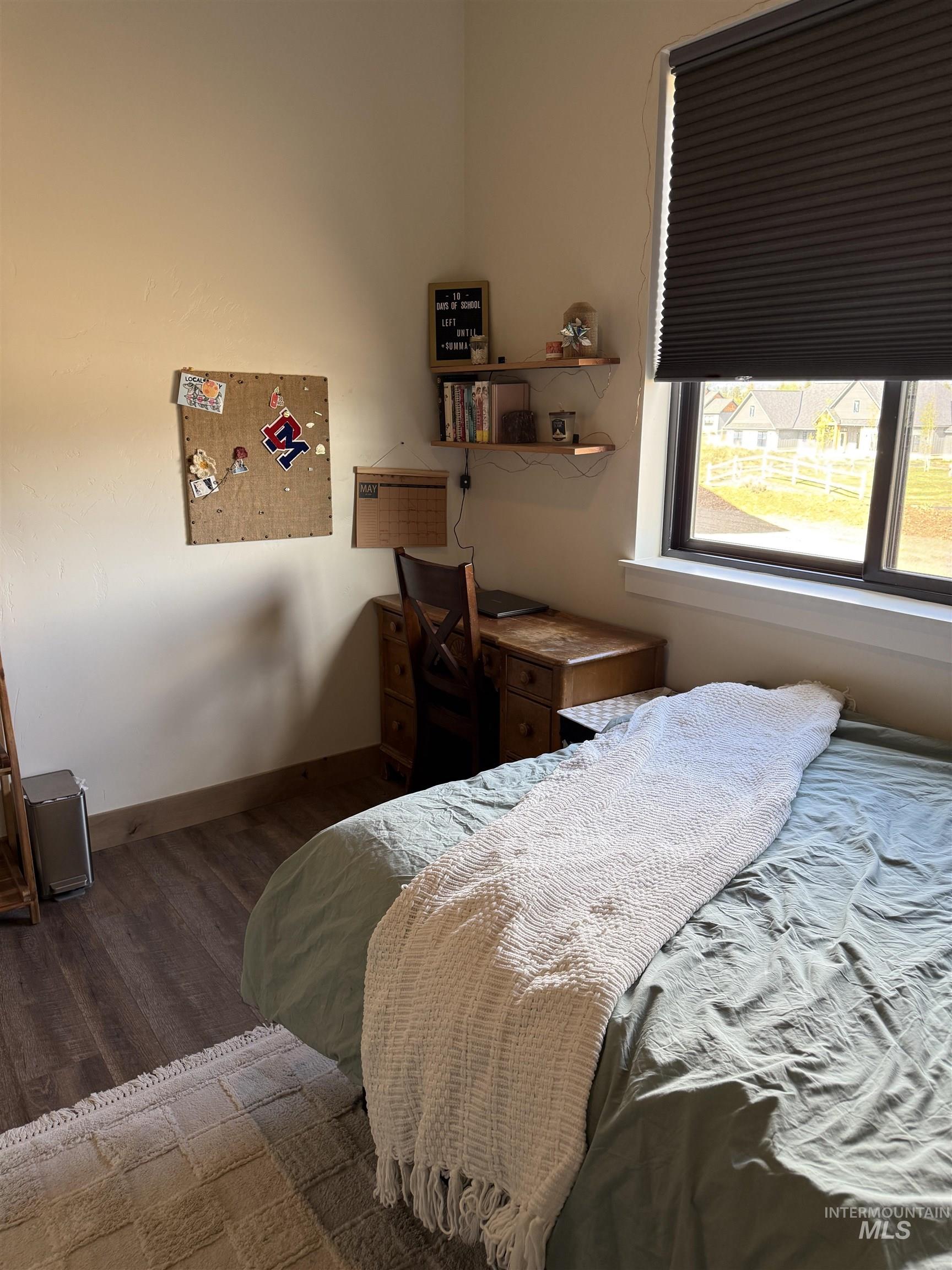 Wood-finish flooring throughout, featuring a window with cellular shades, and built-in floating wall shelves