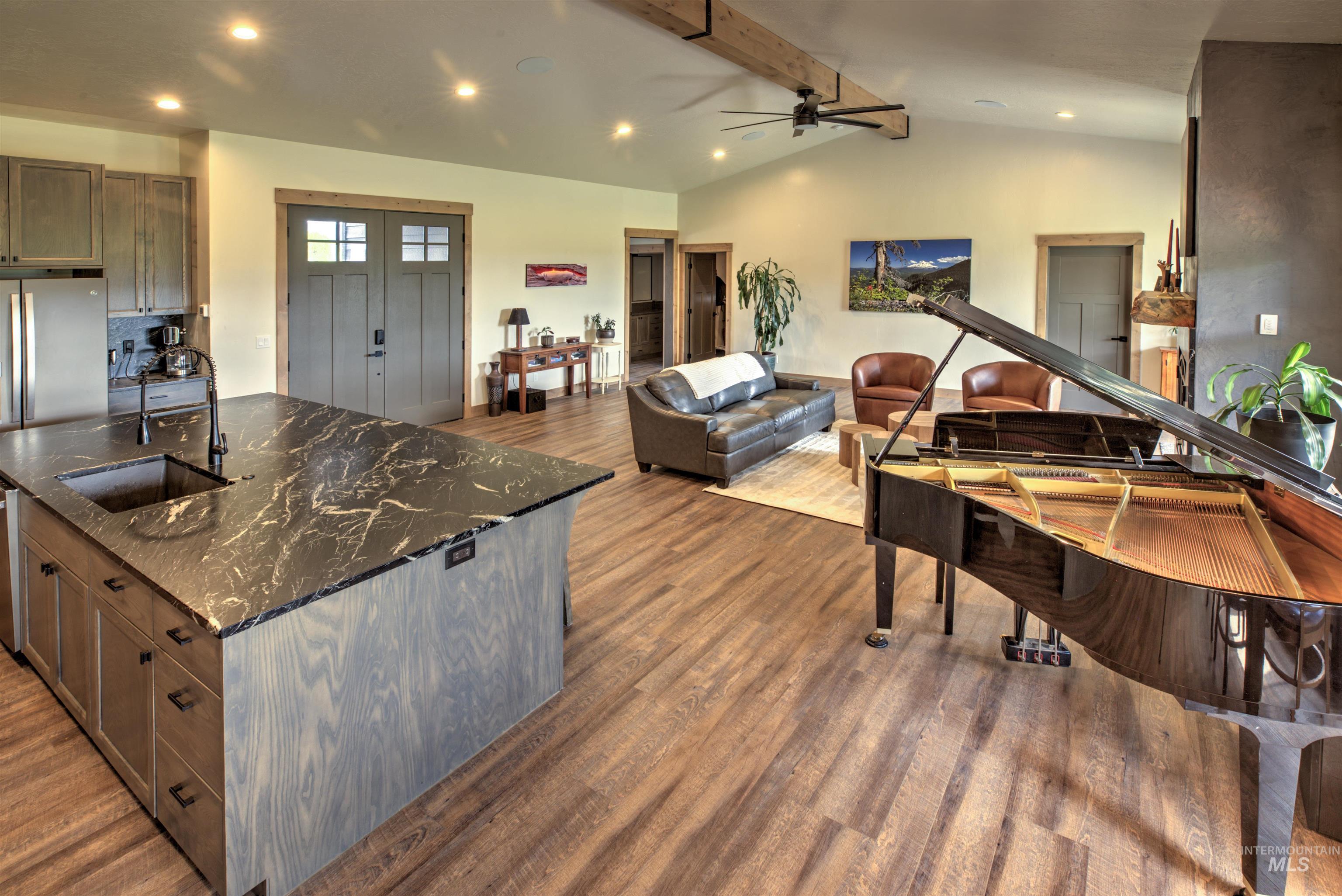 Open-concept living space featuring wood-finish flooring, vaulted ceilings with exposed beam accents, and recessed lighting