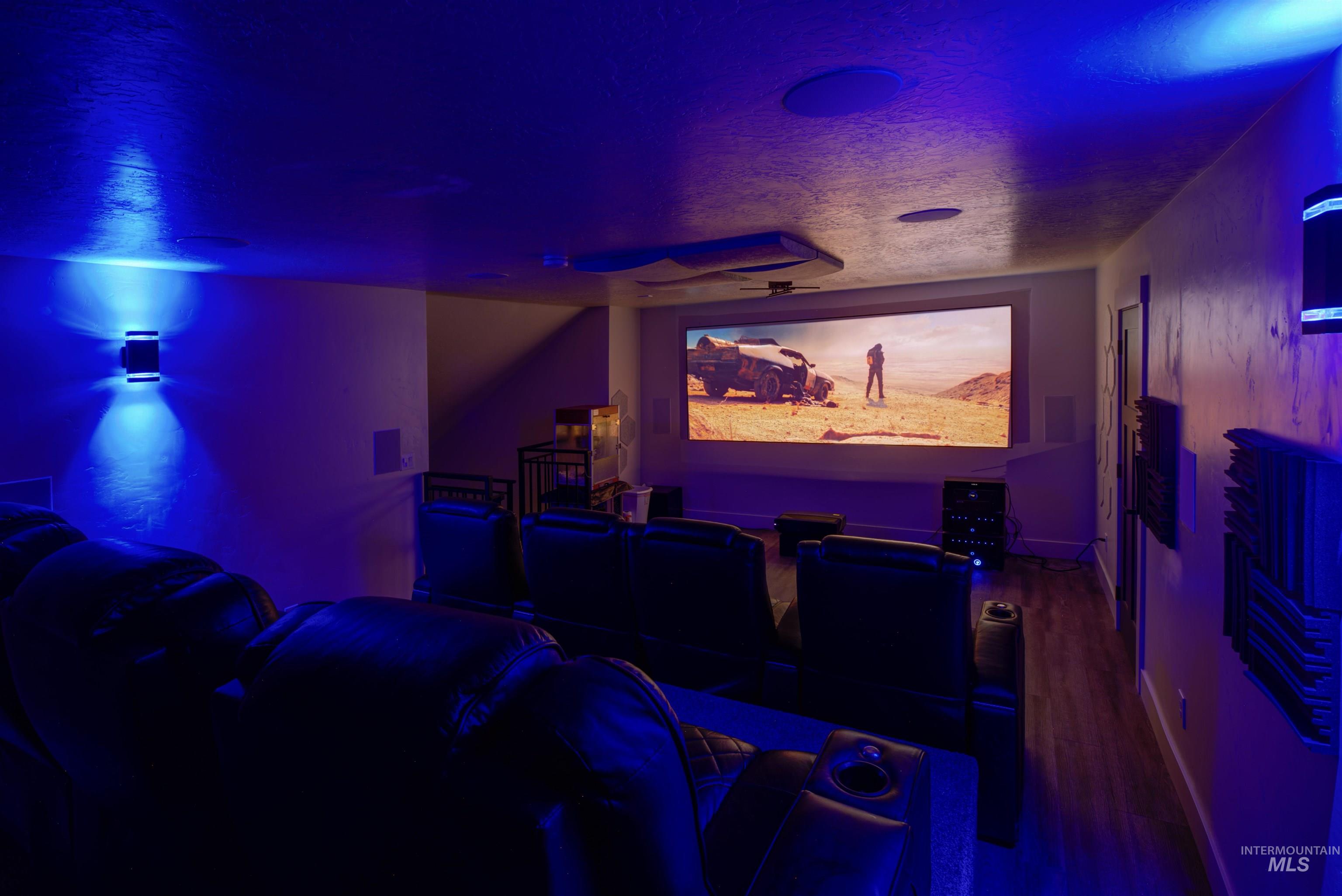 Dedicated media room featuring a large projection screen, built-in wall speakers, and recessed ceiling lighting