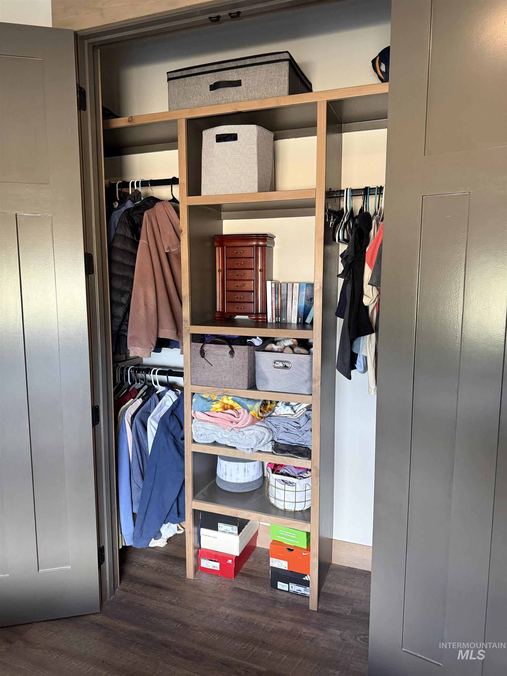 Custom closet system featuring wood-finish shelving and dark wood-finish flooring