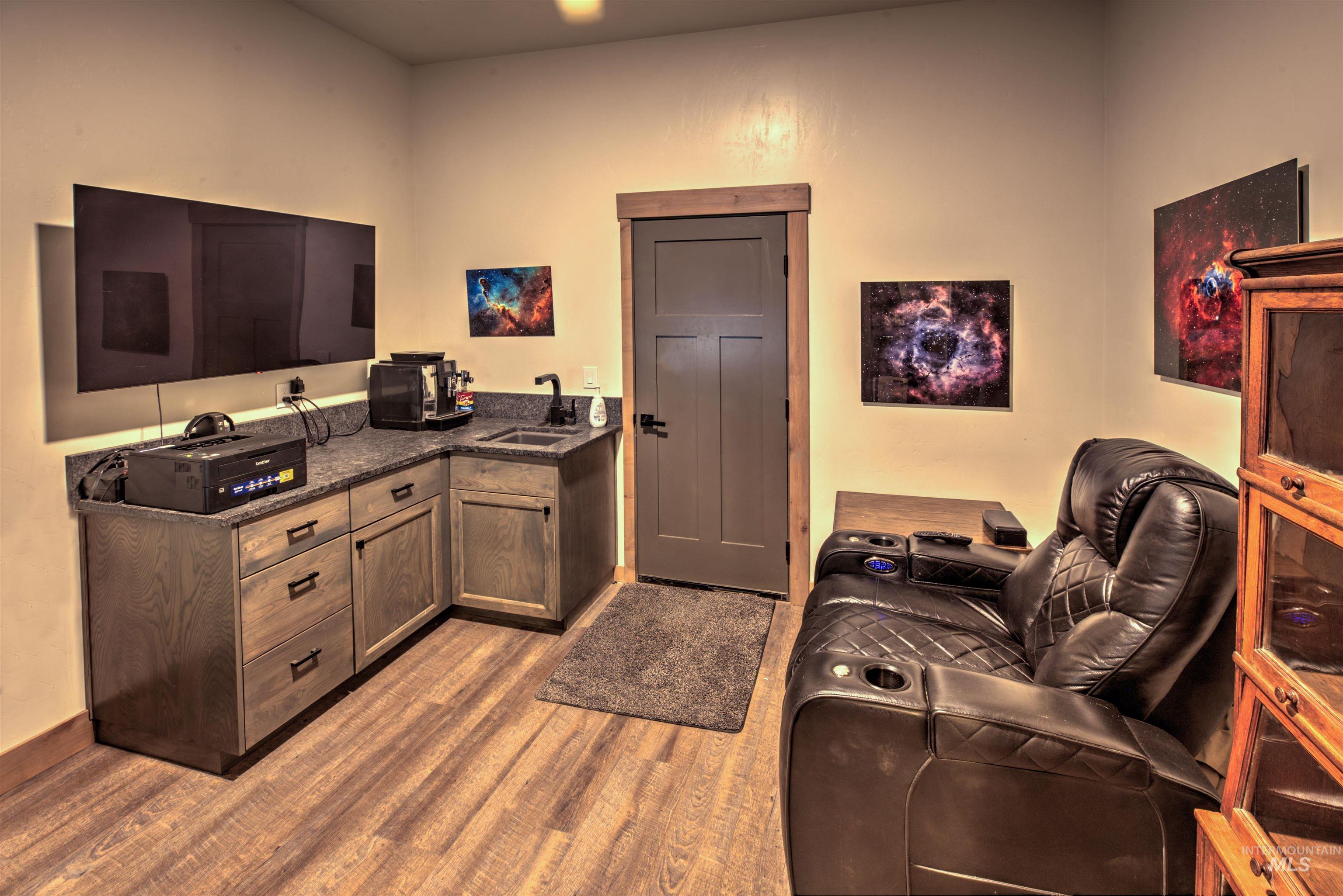 Entertainment area featuring wood-finish flooring and a built-in wet bar with dark cabinetry