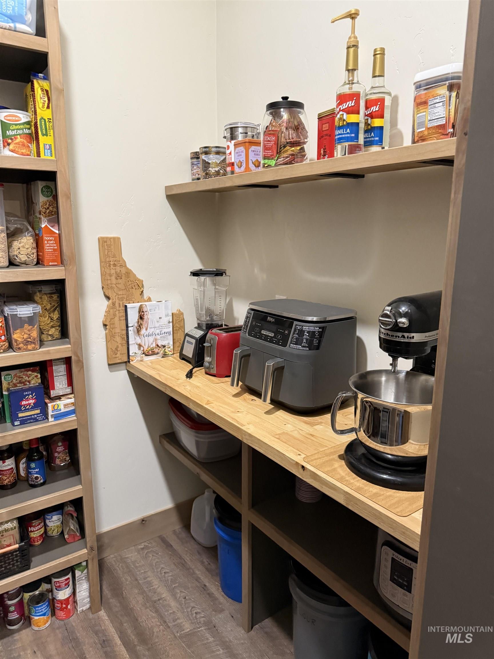 Pantry featuring wood-finish flooring, built-in shelving, and a butcher block countertop