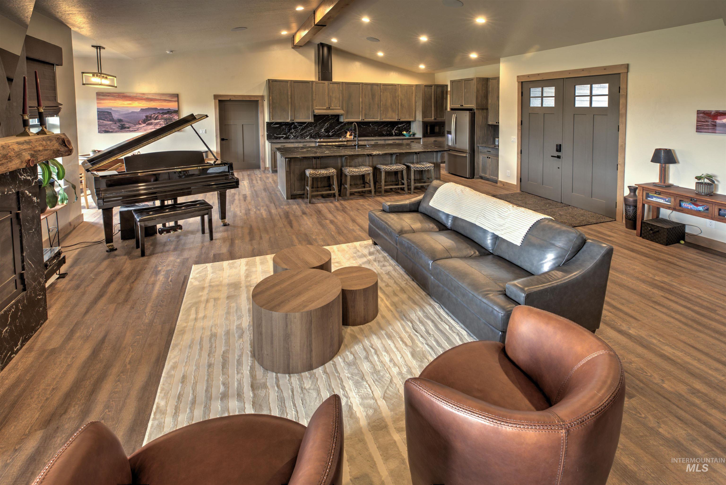 Open concept living area featuring wood-finish flooring, vaulted ceilings with exposed beams, and recessed lighting