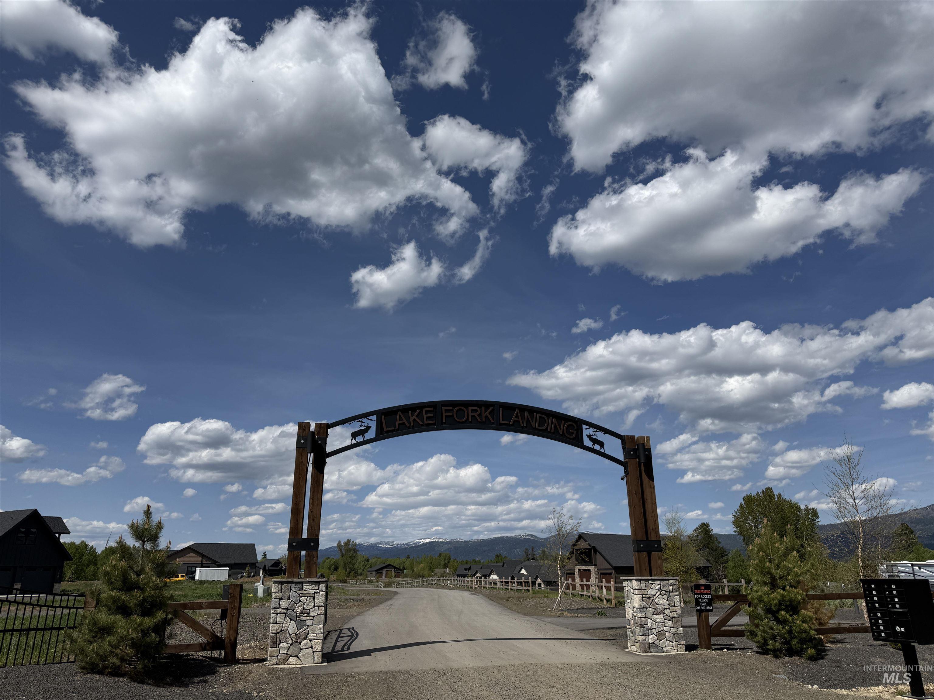 Stone pillar entrance featuring a custom metal archway with decorative wildlife accents
