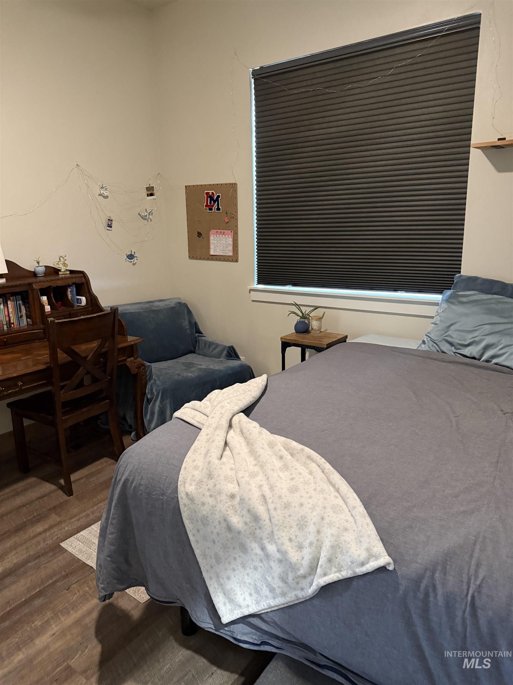 Wood-finish flooring with a window featuring horizontal blinds
