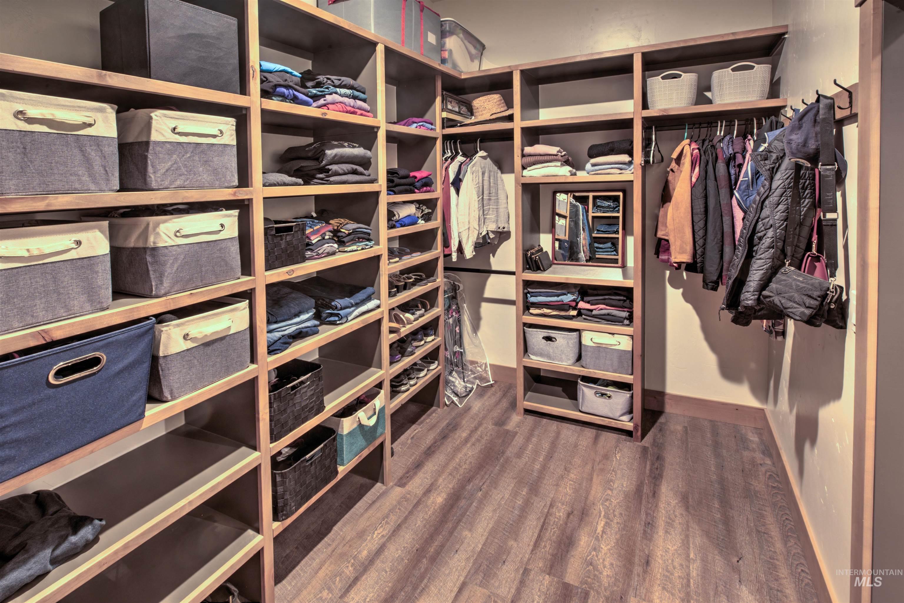 Custom built-in closet system featuring extensive shelving, hanging rods, and wood-finish flooring