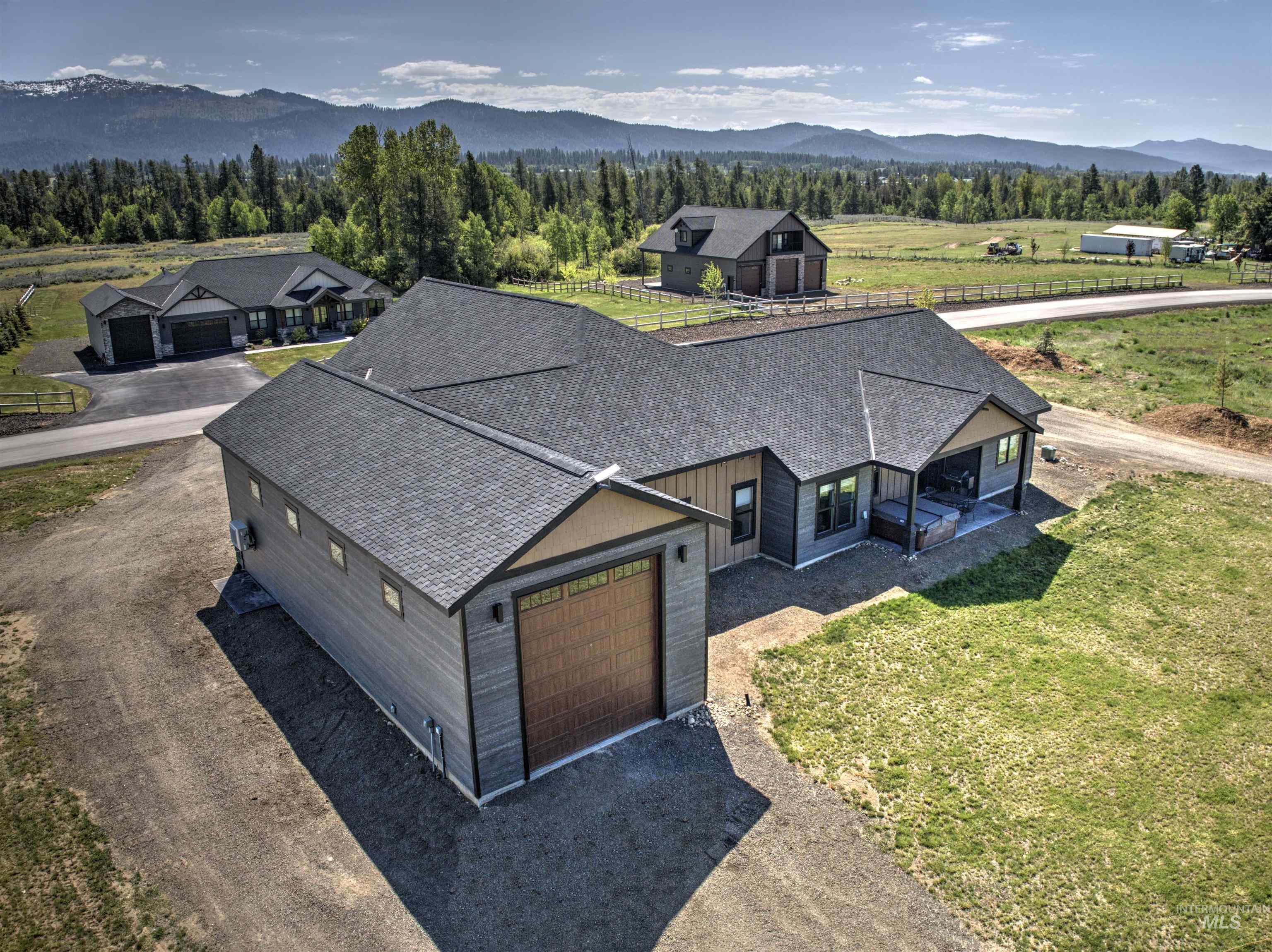 Contemporary residence featuring a detached garage with a wood-finish door, an attached garage, a covered patio, and a shingle roof
