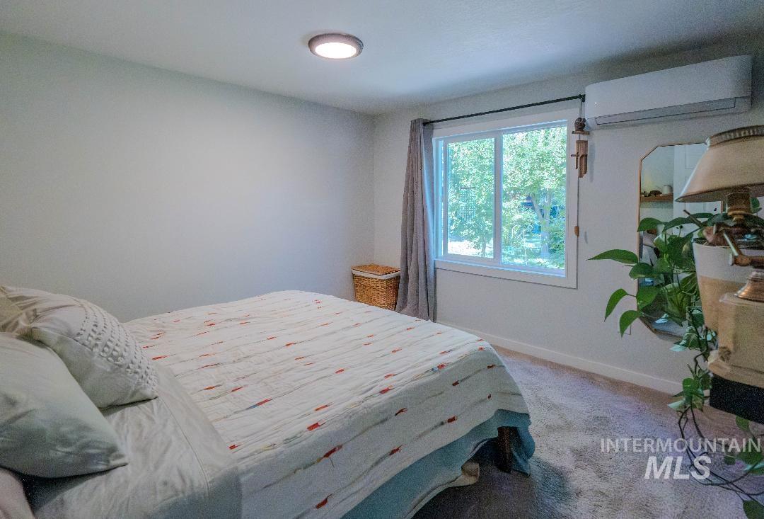 Carpeted bedroom featuring a wall mounted air conditioner and baseboards
