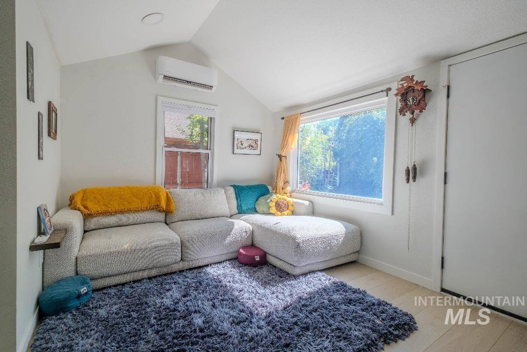 Living room featuring vaulted ceiling and a wall mounted AC