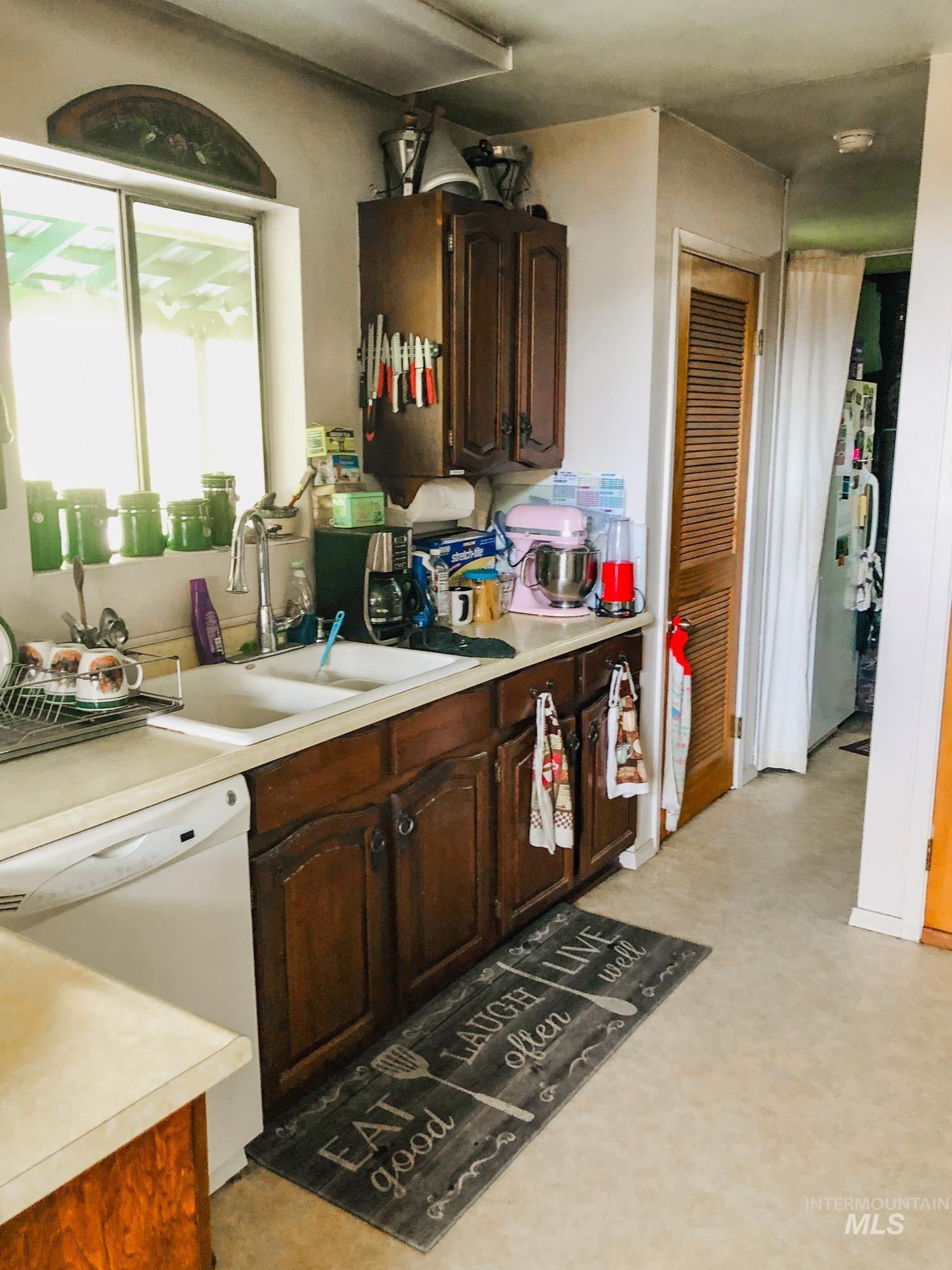 Kitchen featuring white appliances, light countertops, and dark brown cabinetry