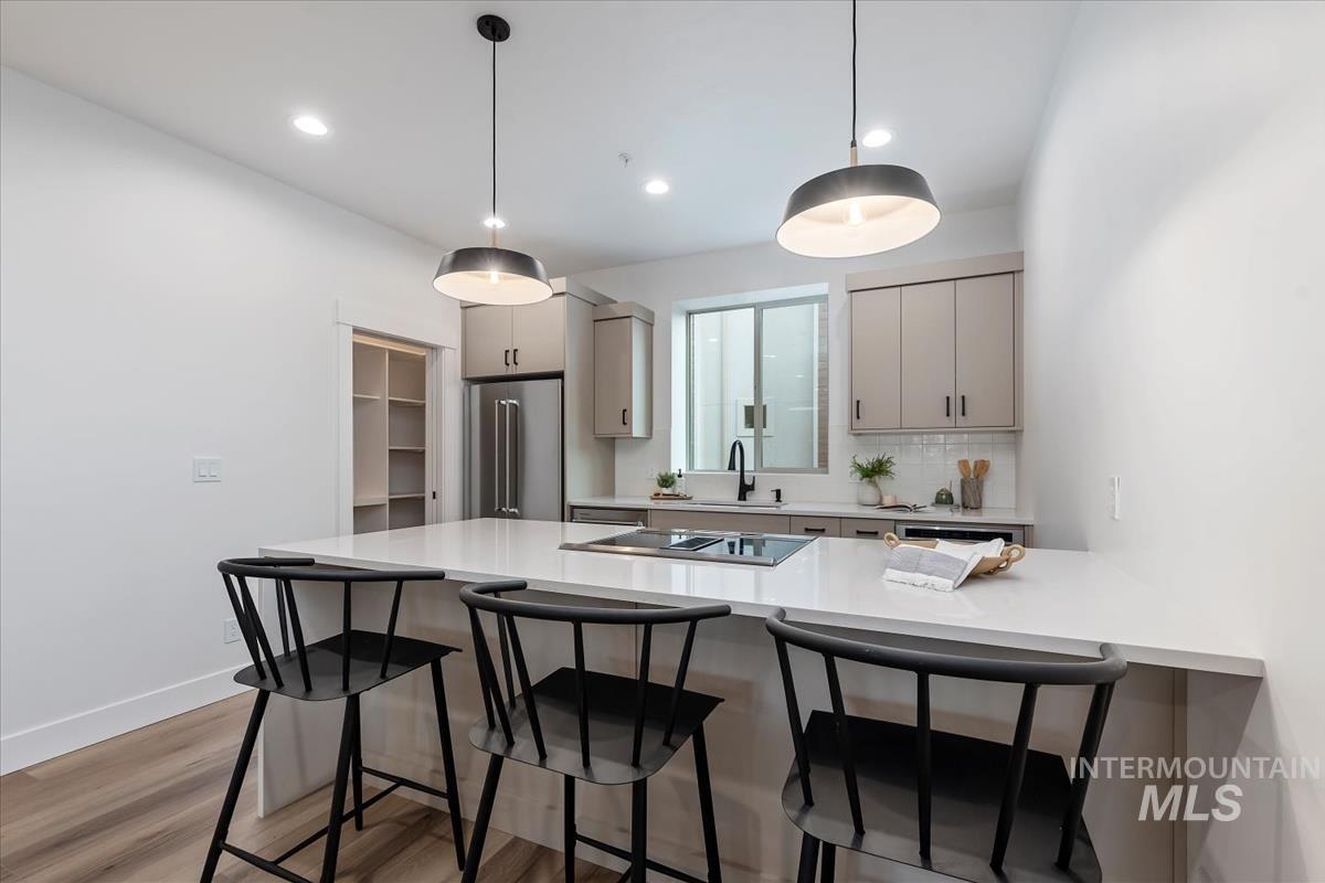 Kitchen featuring a kitchen breakfast bar, gray cabinetry, a peninsula, light wood-style floors, and high end fridge