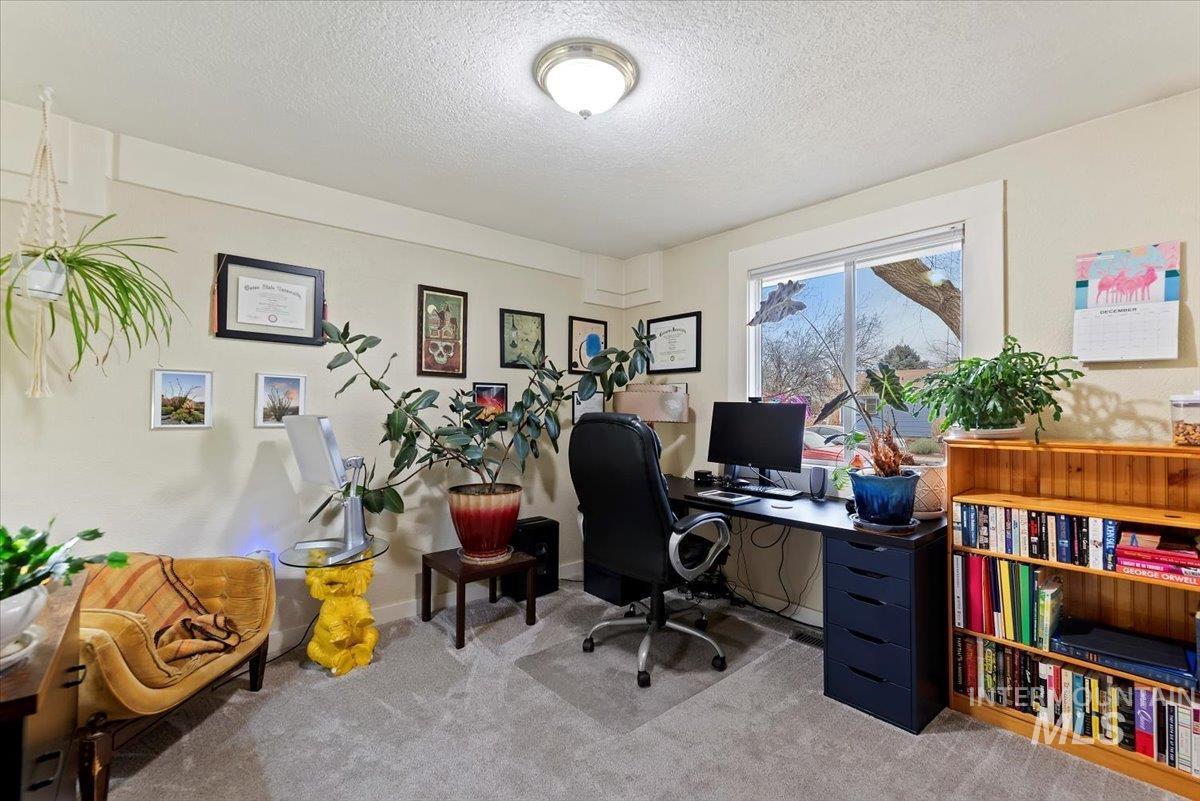 Carpeted home office featuring a textured ceiling