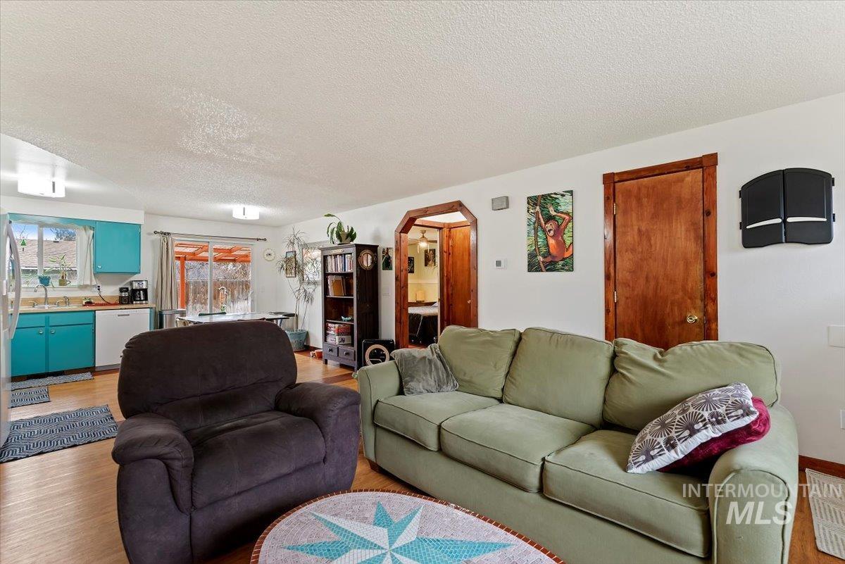 Living room featuring a textured ceiling, arched walkways, and light wood finished floors