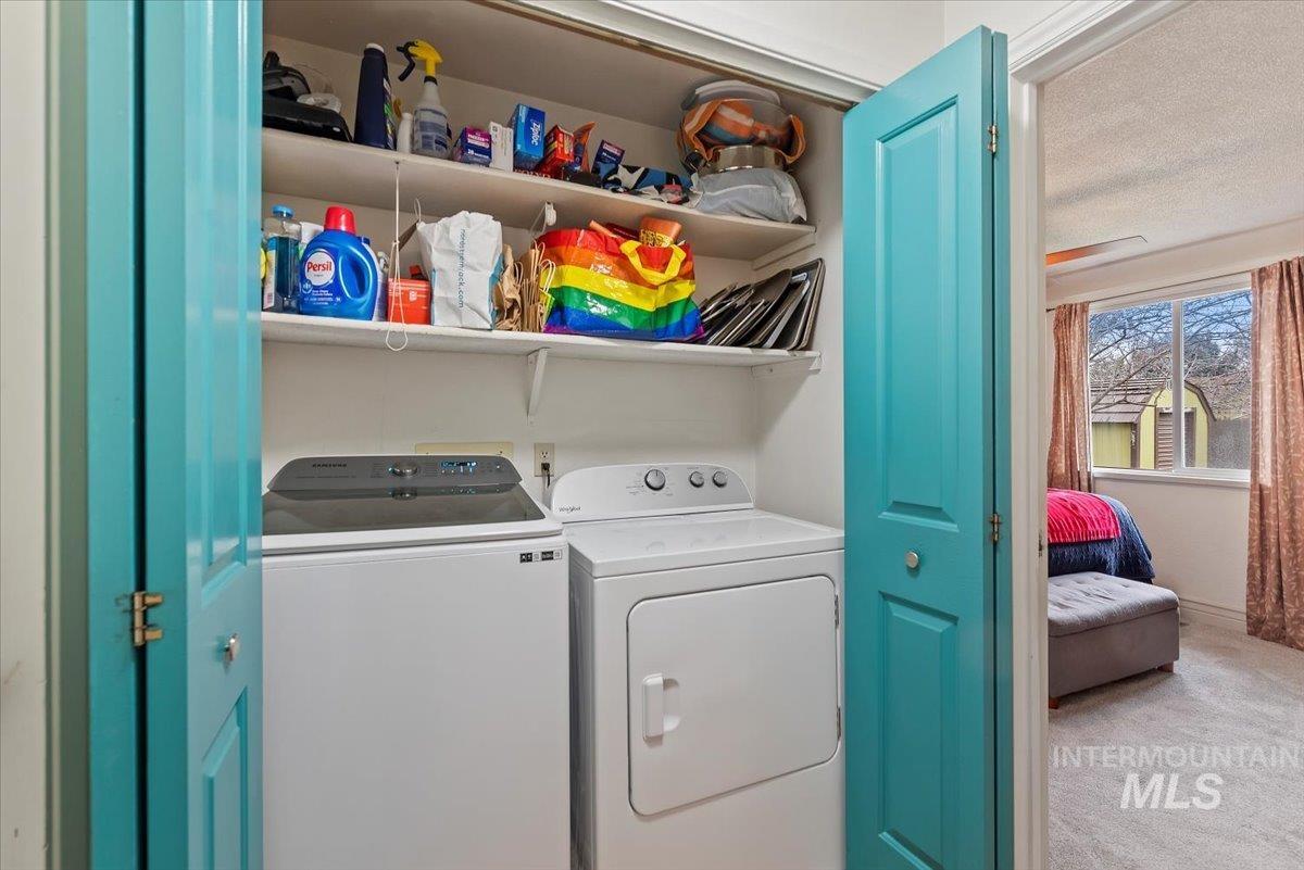 Laundry area featuring a textured ceiling, carpet flooring, and washer and dryer