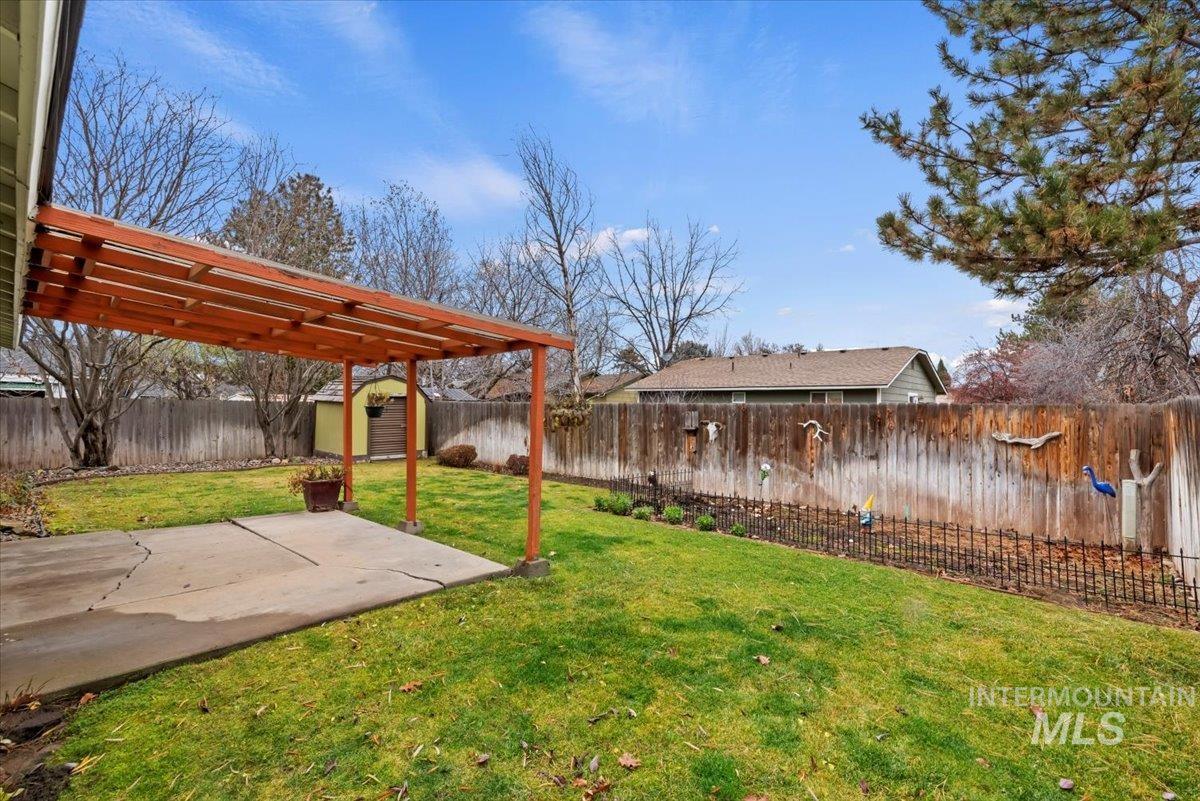 Fenced backyard featuring a shed and a patio area