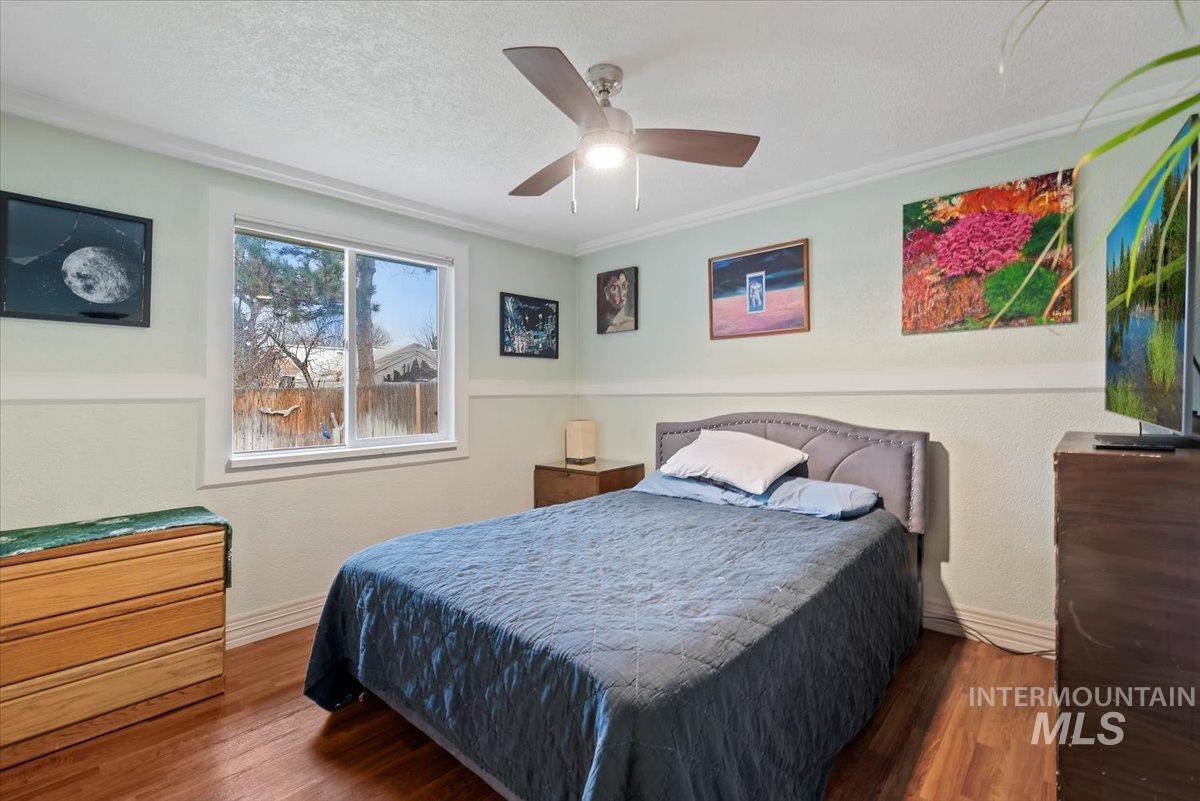 Bedroom with wood finished floors, a textured ceiling, ceiling fan, and a textured wall
