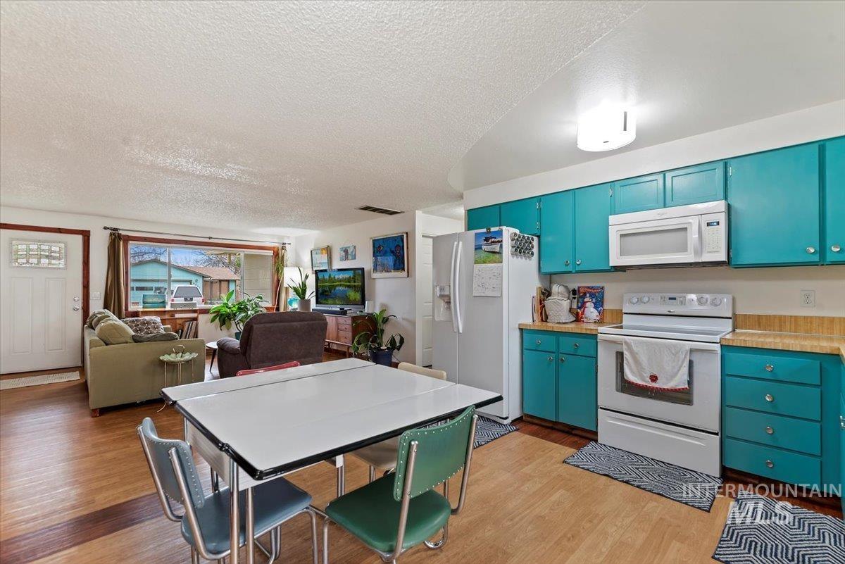 Kitchen with white appliances, light countertops, a textured ceiling, light wood-style floors, and blue cabinets