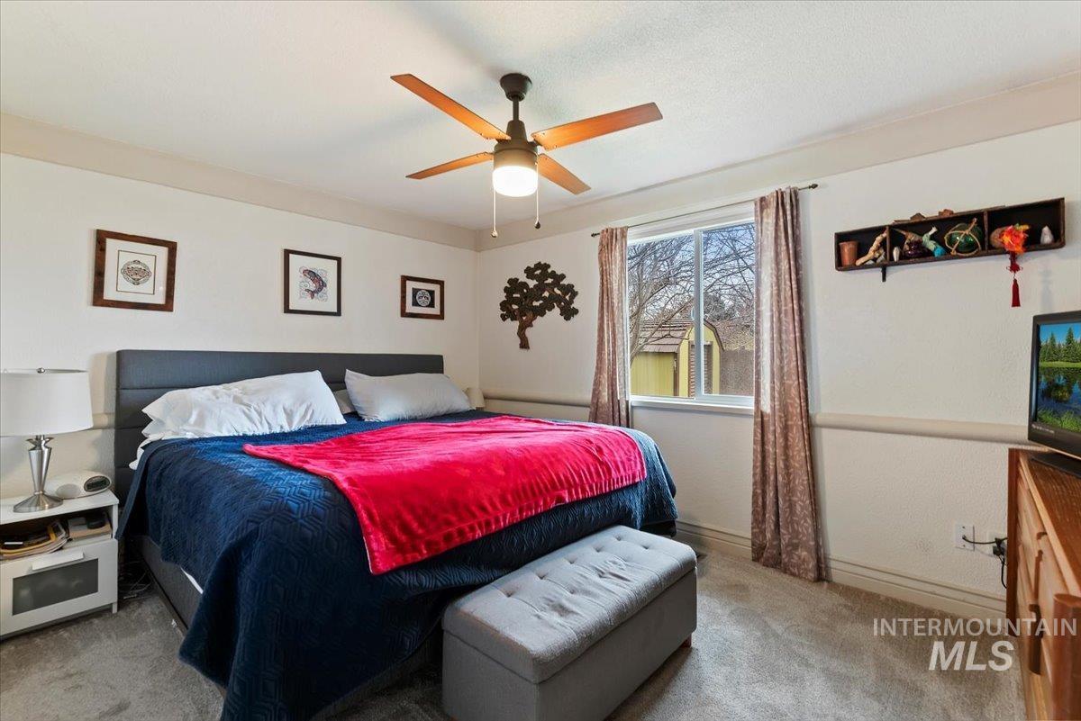 Carpeted bedroom featuring ceiling fan and baseboards