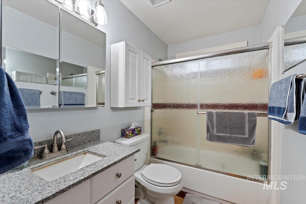 Full bath with combined bath / shower with glass door and vanity