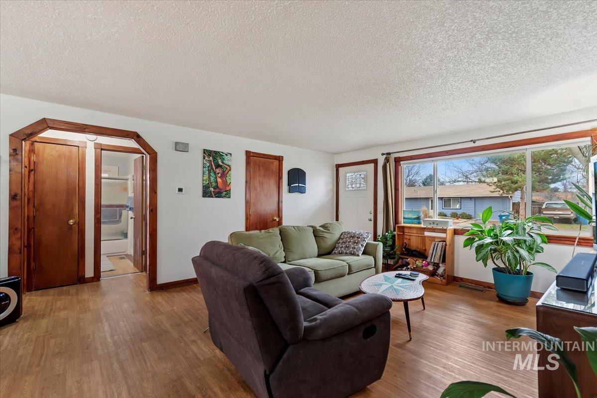 Living room featuring a textured ceiling, wood finished floors, and arched walkways