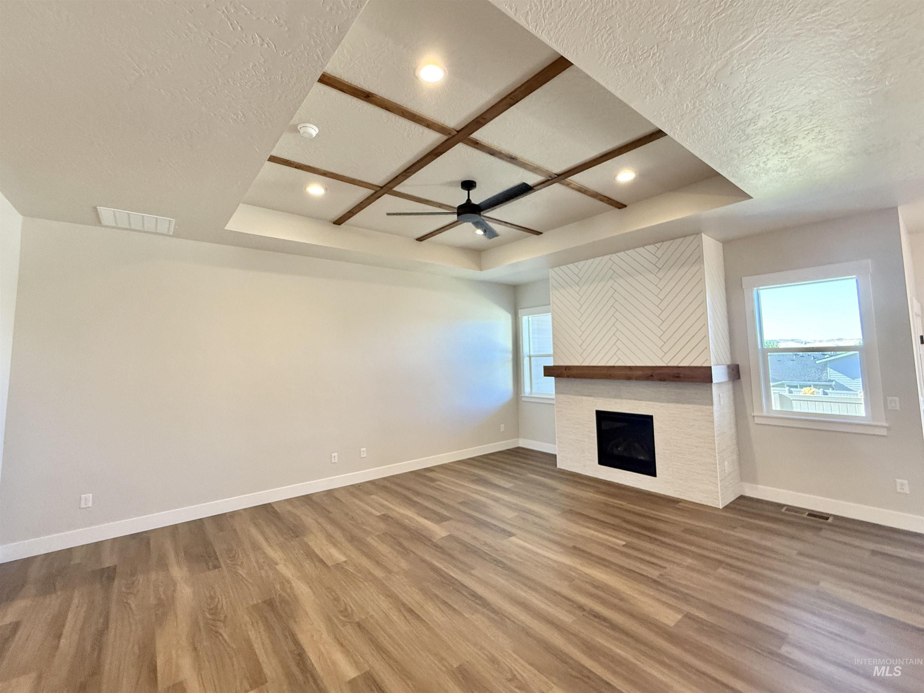 Unfurnished living room featuring a textured ceiling, wood finished floors, ceiling fan, a large fireplace, and recessed lighting