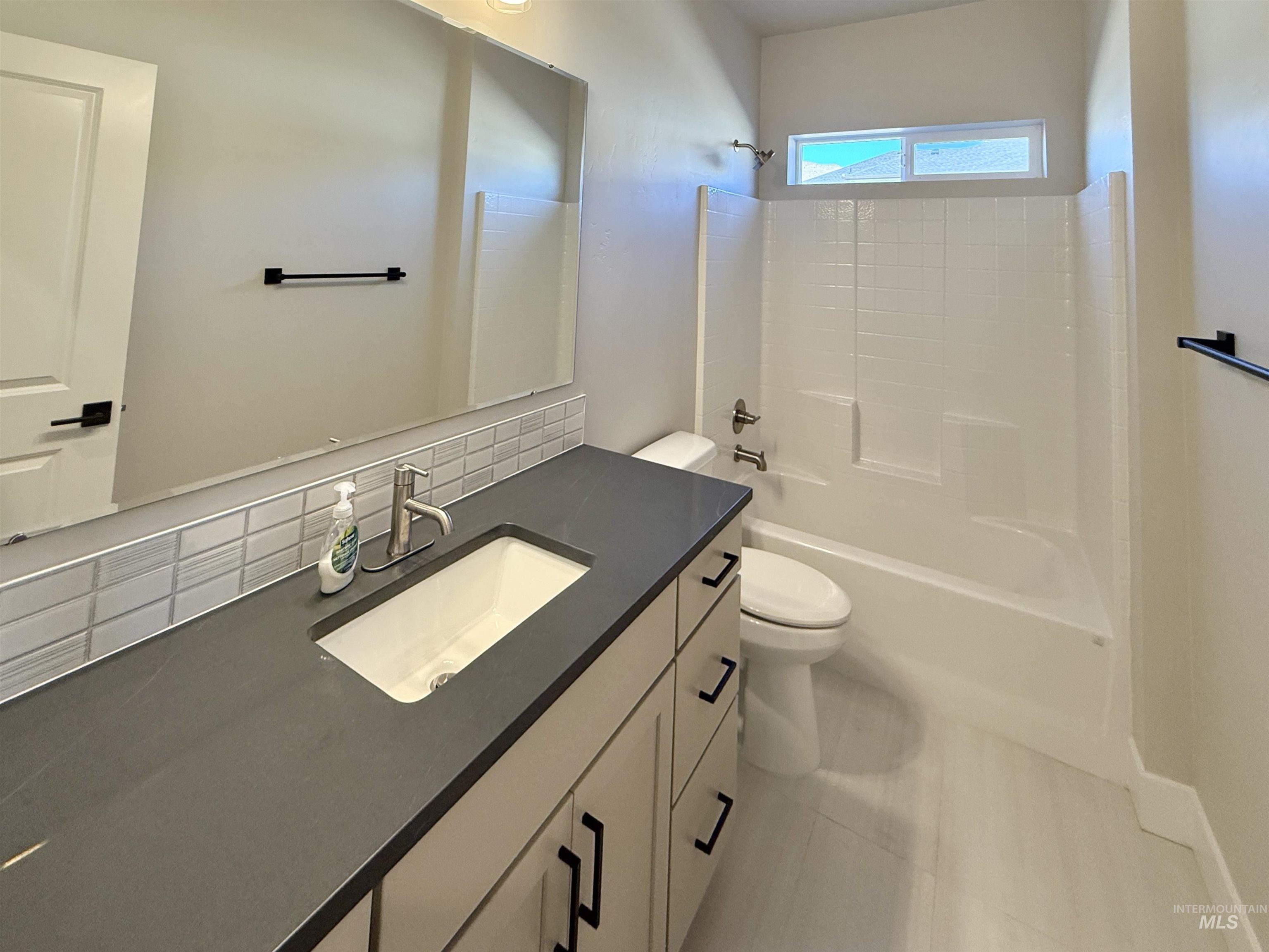 Bathroom featuring decorative backsplash, shower / tub combination, vanity, and light tile patterned flooring