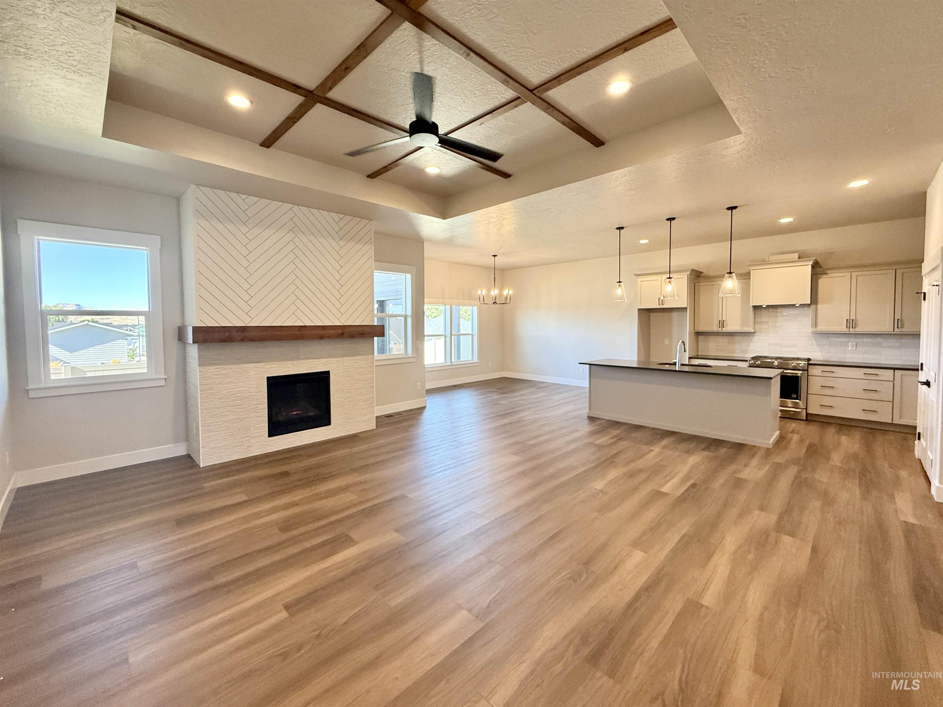 Unfurnished living room featuring a tray ceiling, a ceiling fan, recessed lighting, a chandelier, and a textured ceiling
