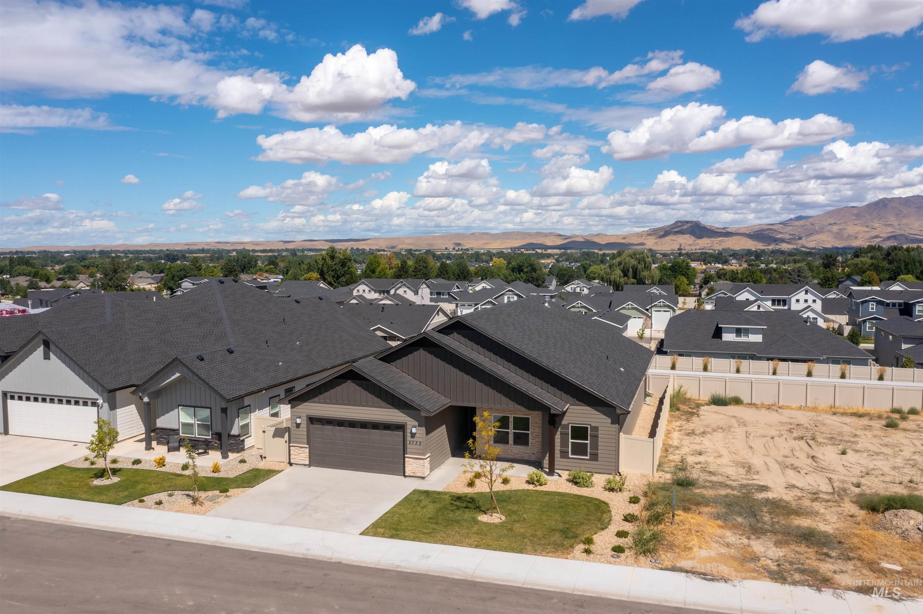 View of front of property featuring board and batten siding, a residential view, driveway, roof with shingles, and a mountain view