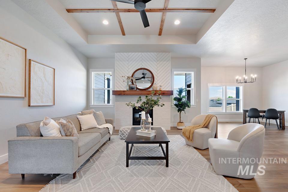 Living room with light wood-style floors, a raised ceiling, healthy amount of natural light, and recessed lighting
