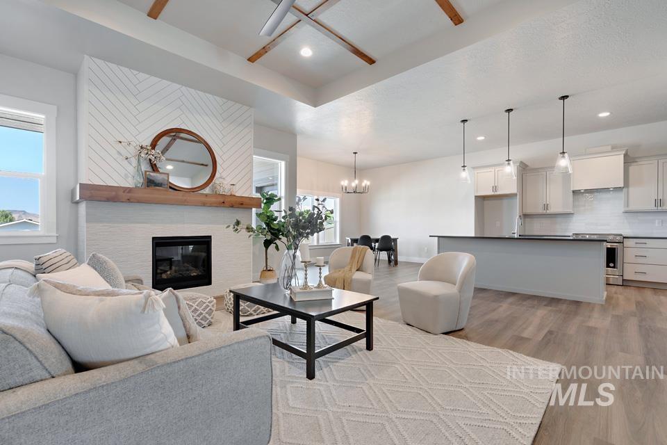 Living area featuring light wood-style flooring, a fireplace, a chandelier, recessed lighting, and a ceiling fan