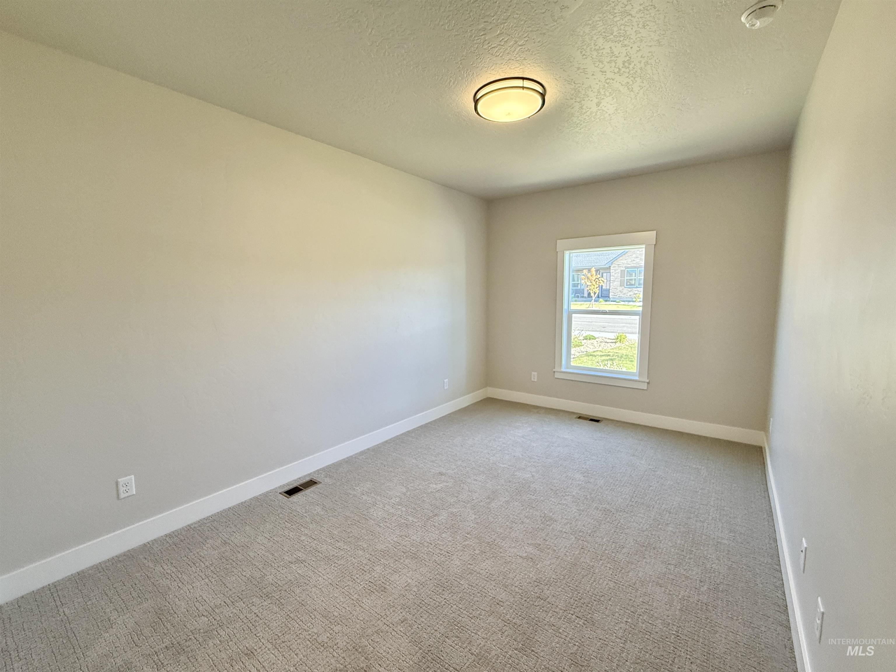 Unfurnished room featuring a textured ceiling and carpet floors