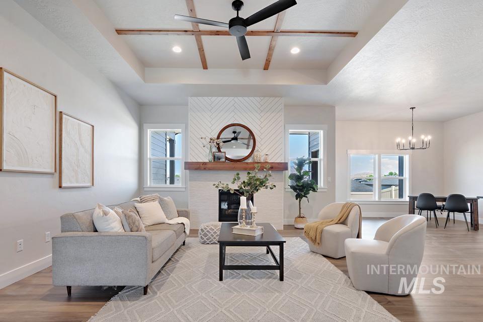 Living area with a tray ceiling, light wood-style floors, a fireplace, ceiling fan, and recessed lighting