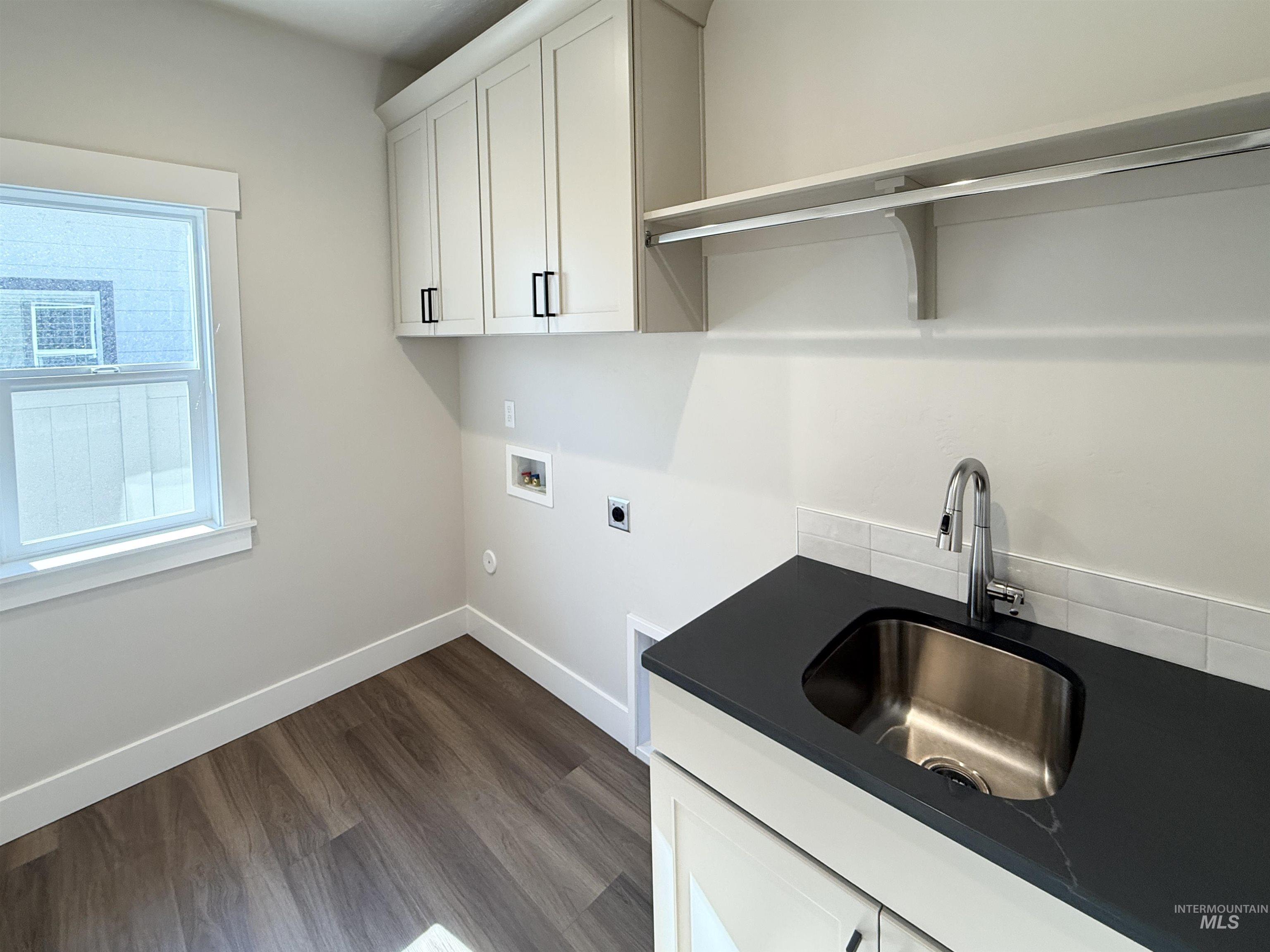 Washroom with dark wood finished floors, cabinet space, hookup for a washing machine, and electric dryer hookup