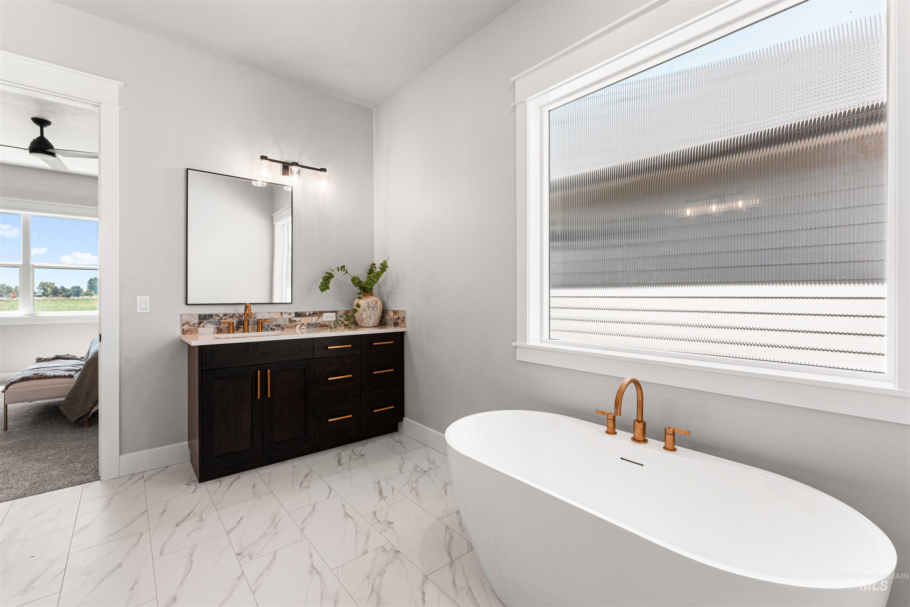 Bathroom featuring a freestanding bath, vanity, and marble look tiles