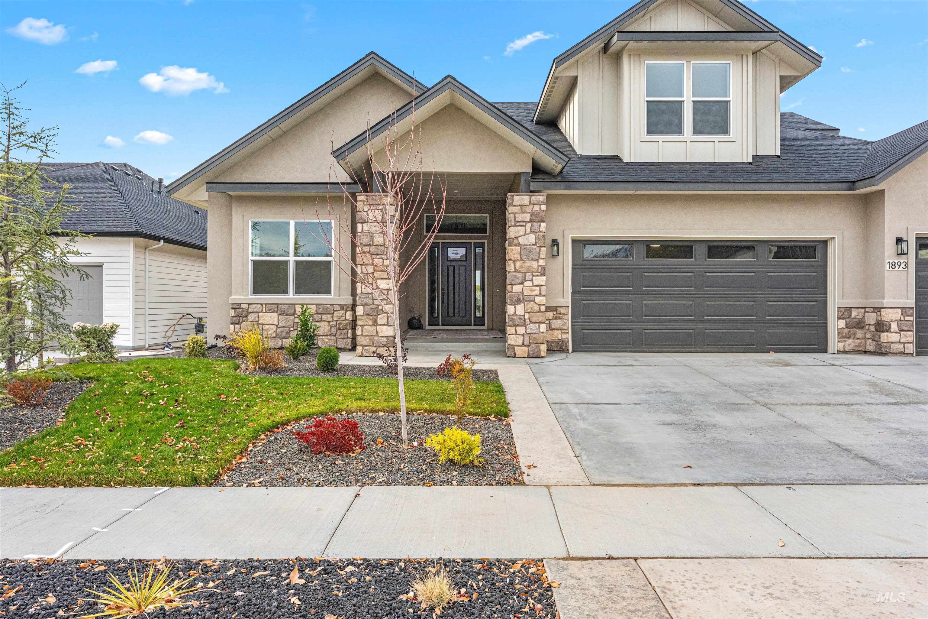 View of front of house featuring board and batten siding, stone siding, concrete driveway, a front yard, and a garage