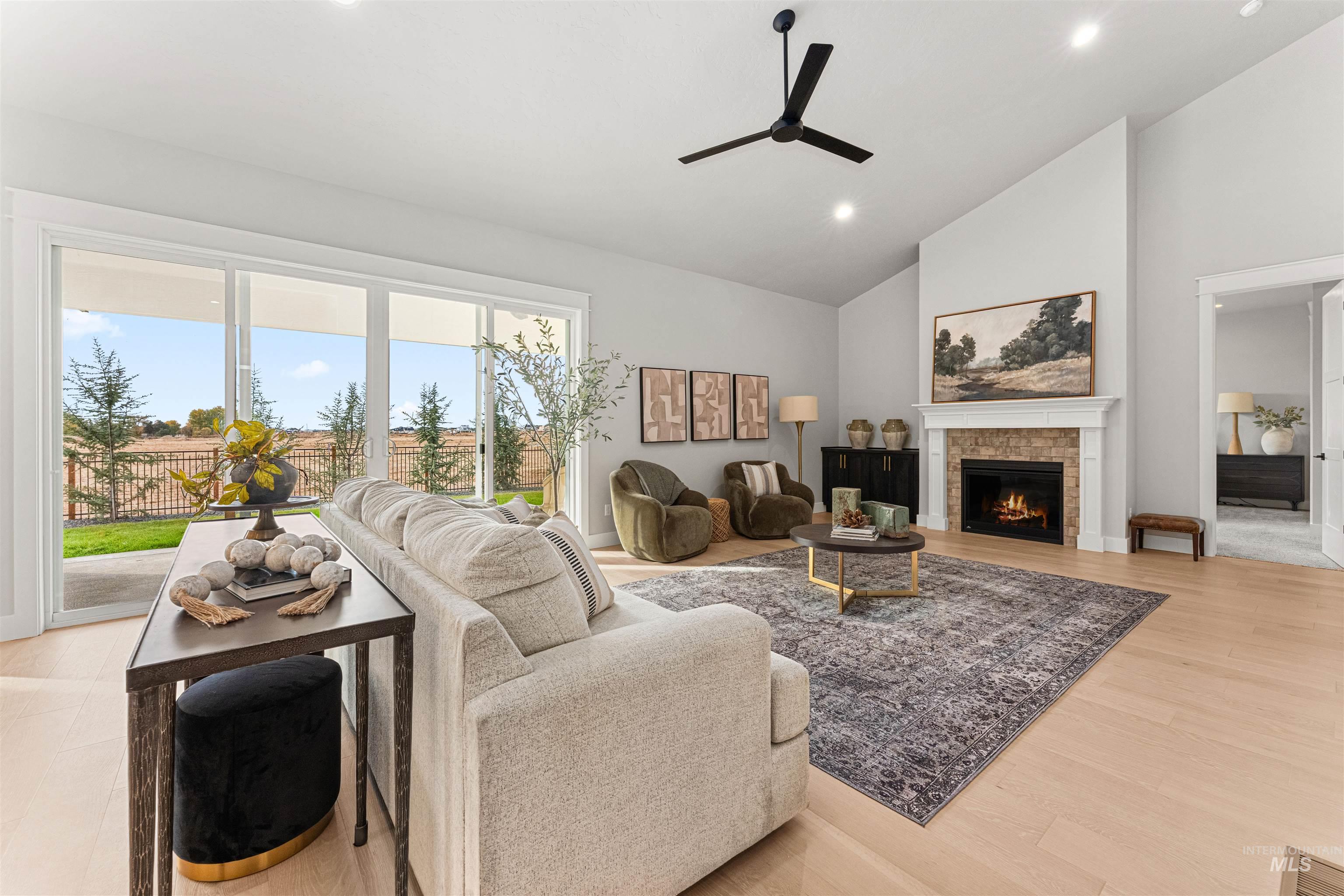 Living area featuring recessed lighting, a lit fireplace, high vaulted ceiling, ceiling fan, and light wood-type flooring