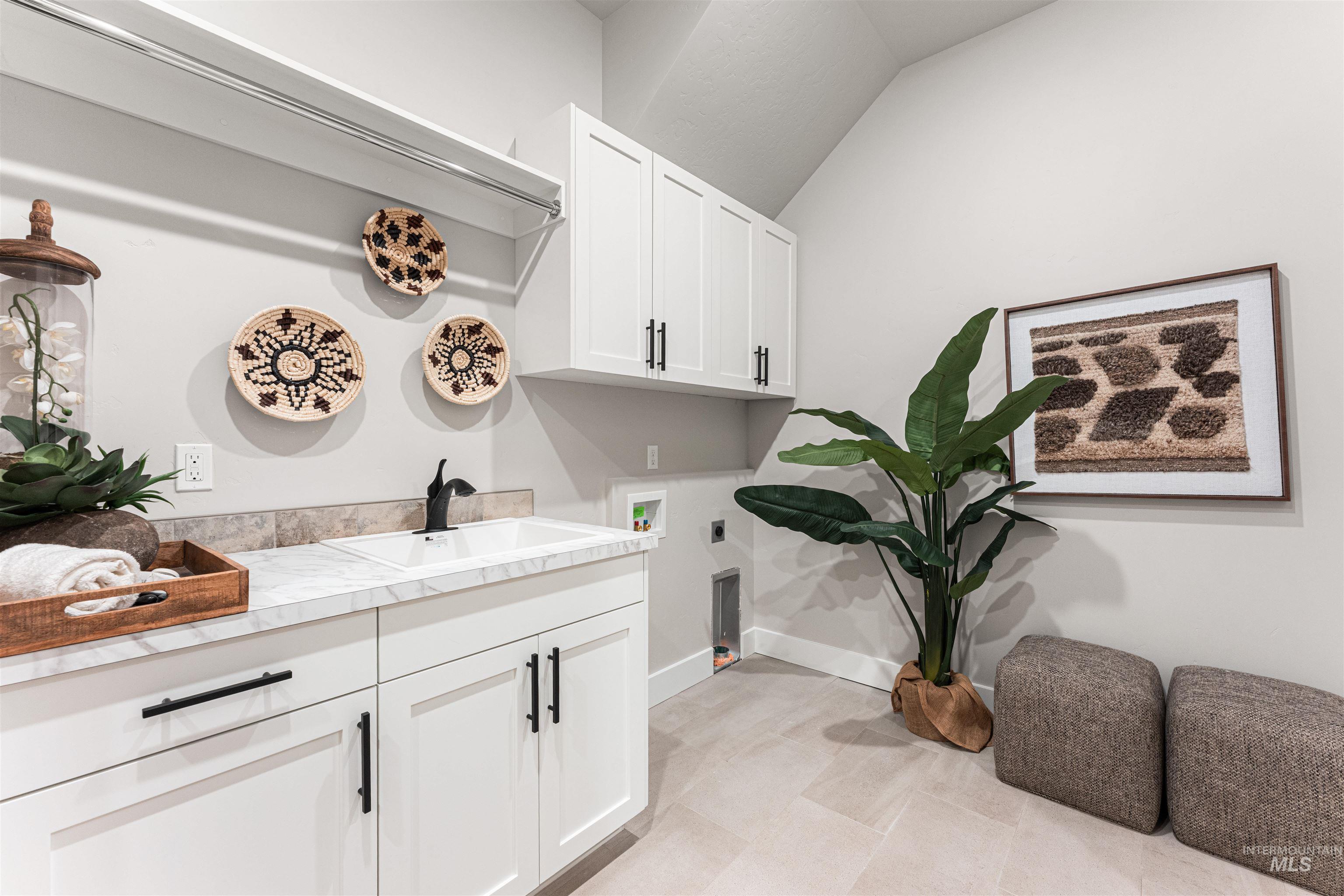 Washroom with hookup for an electric dryer, cabinet space, and hookup for a washing machine