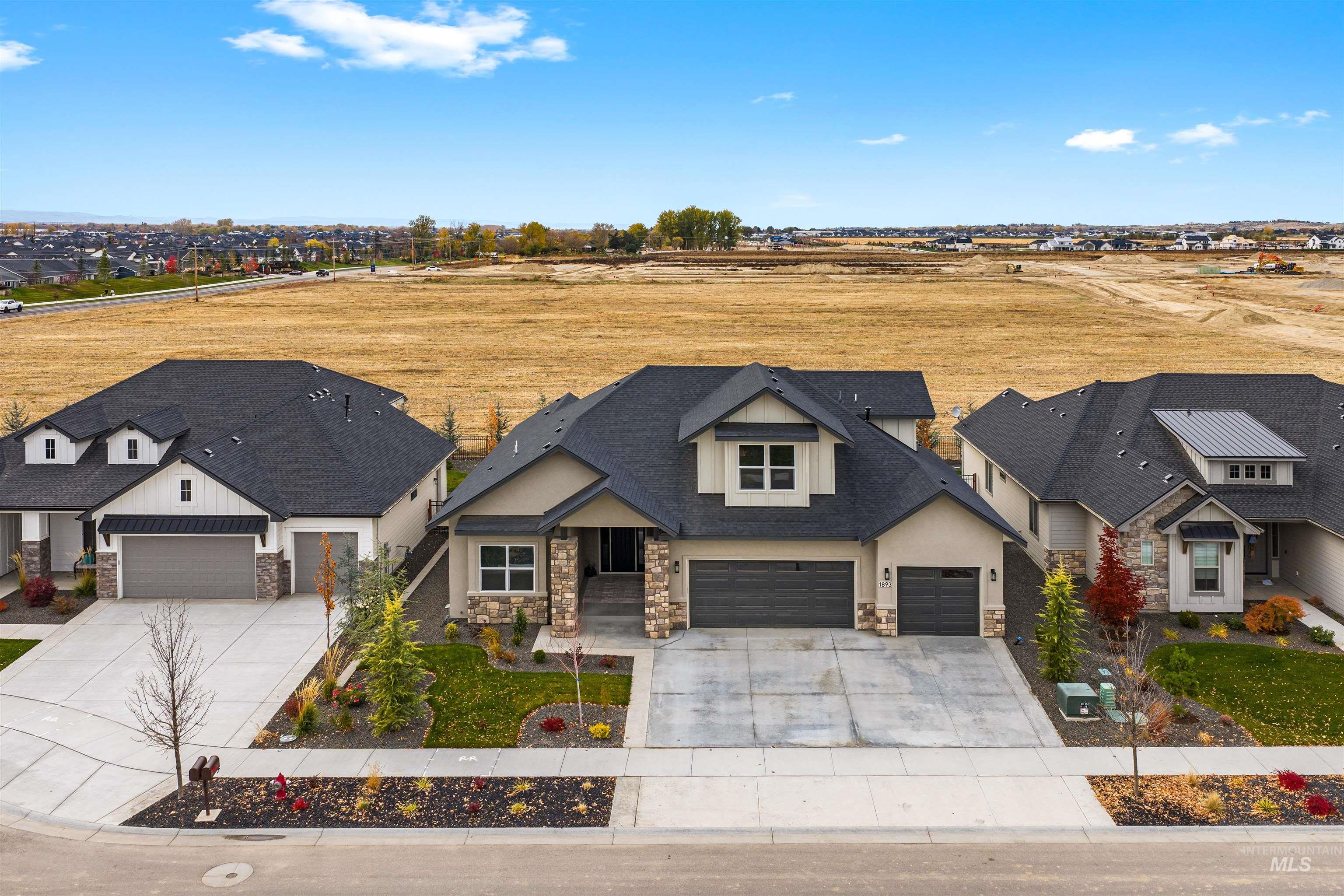 View of front of house featuring stone siding, driveway, a garage, and a shingled roof