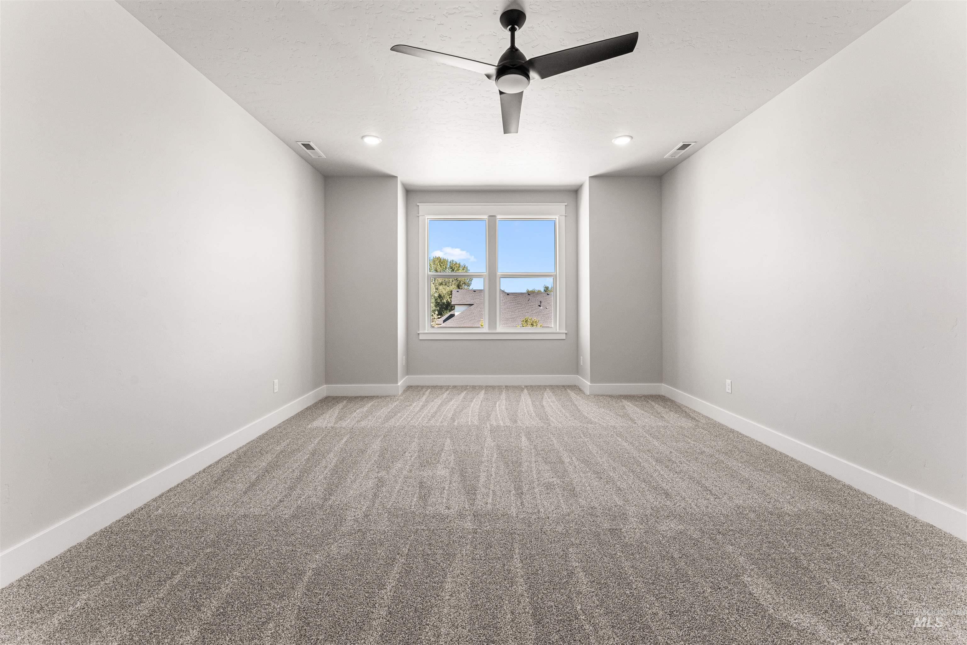Unfurnished room featuring light colored carpet, ceiling fan, and a textured ceiling