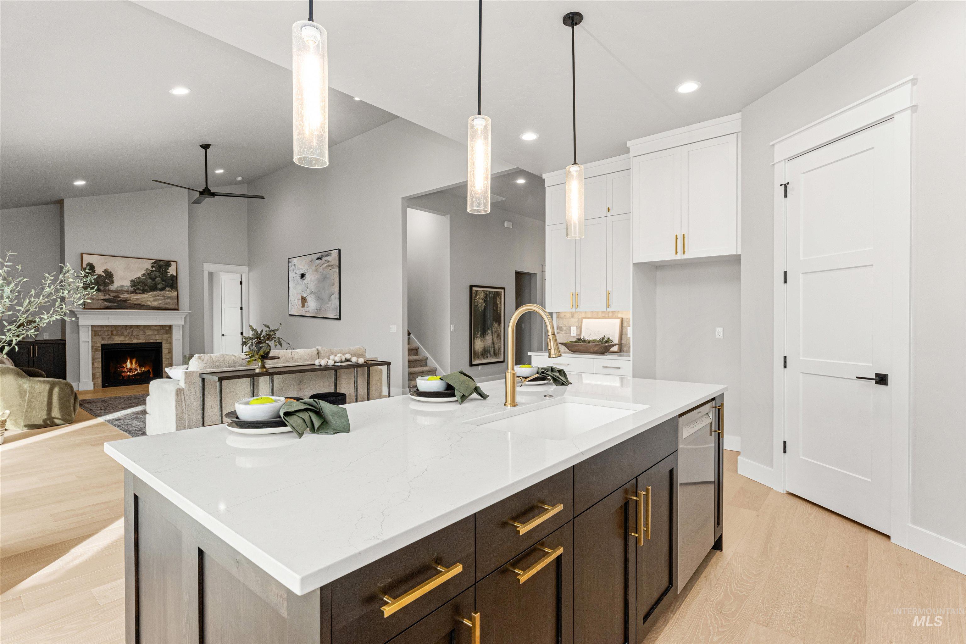 Kitchen with ceiling fan, a stone fireplace, dark brown cabinetry, white cabinets, and decorative light fixtures