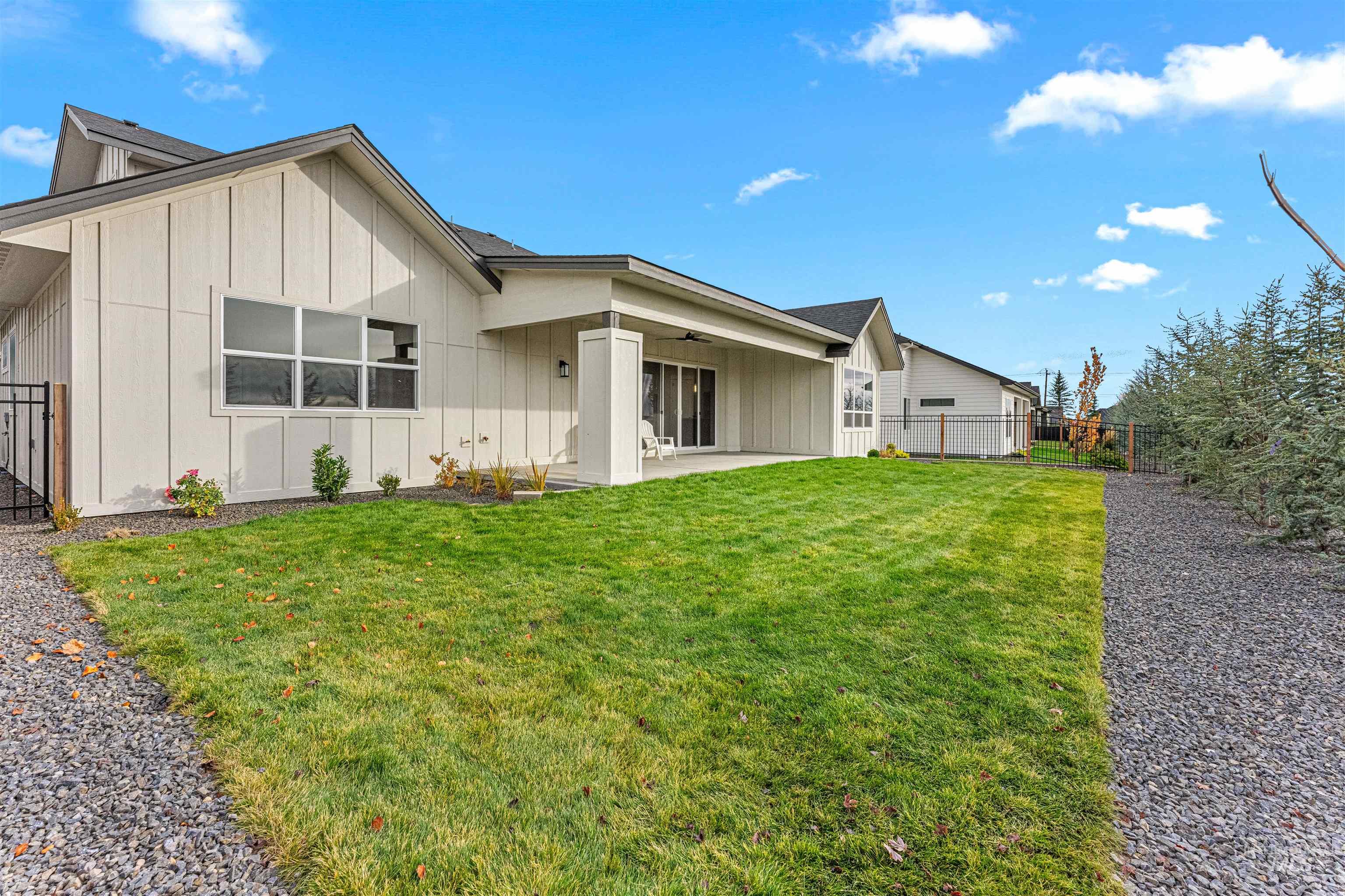 View of front of home featuring board and batten siding, a fenced backyard, and a ceiling fan