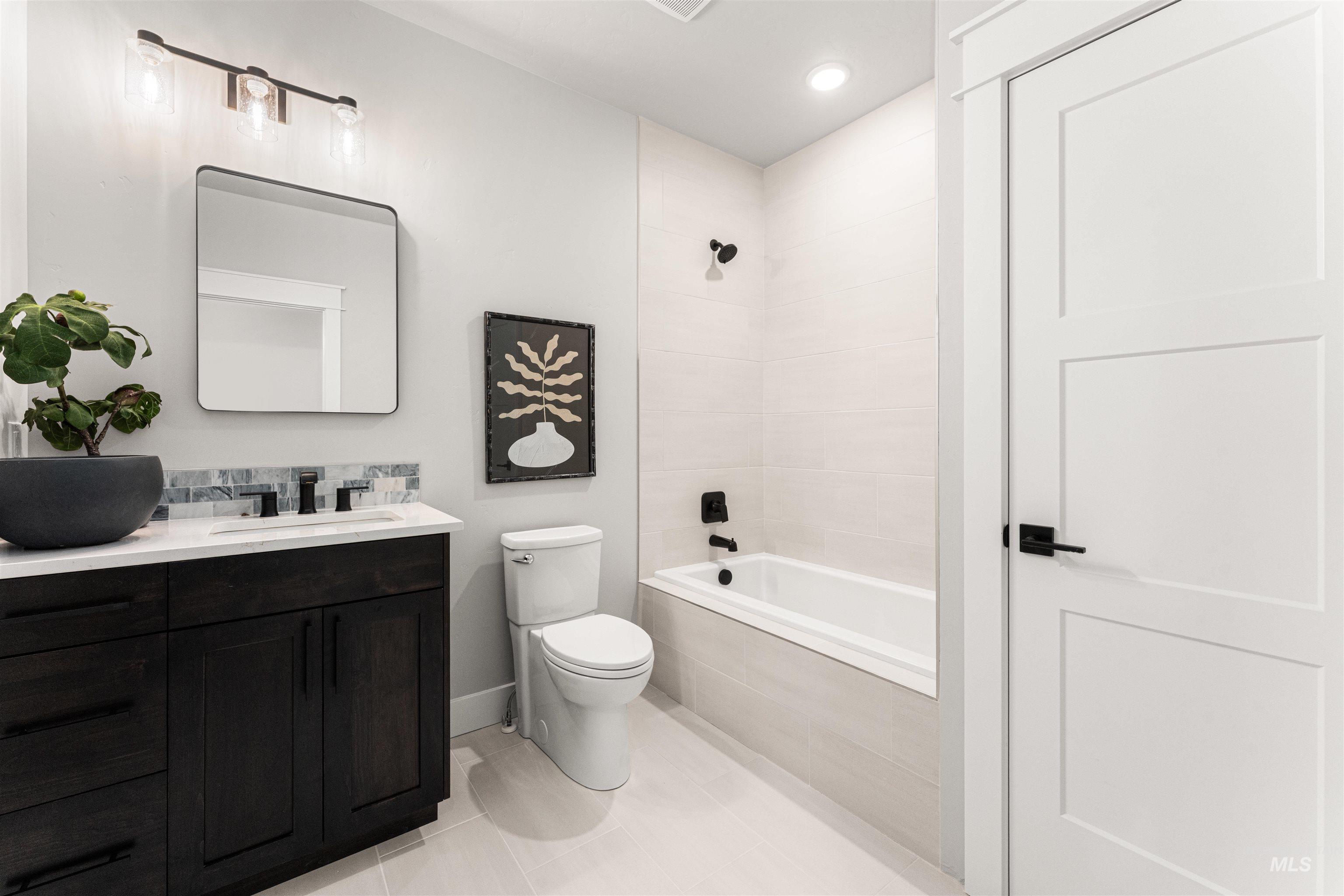 Bathroom with vanity, tiled shower / bath combo, tile patterned flooring, and recessed lighting