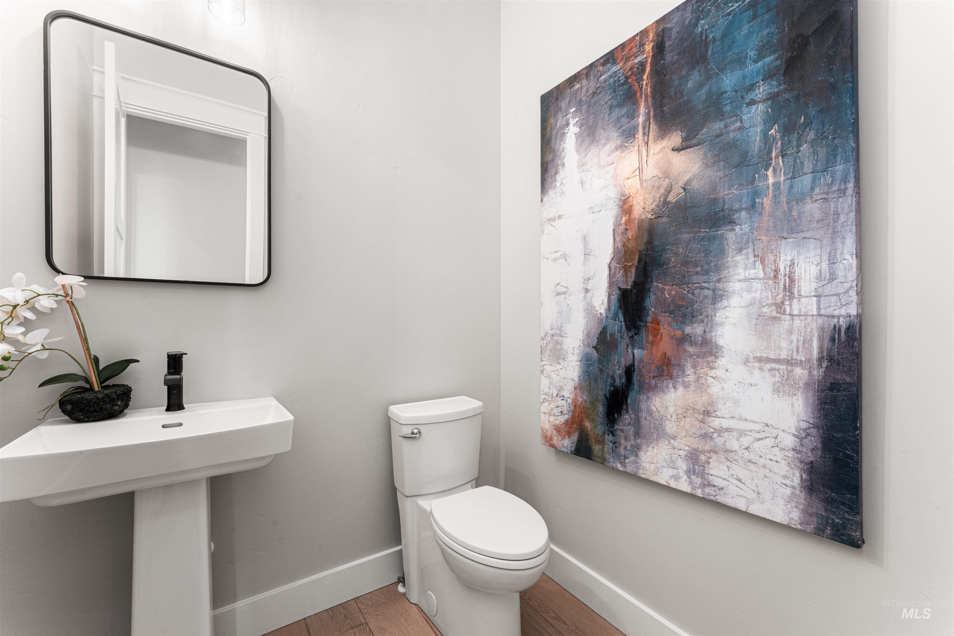 Half bathroom with toilet and wood finished floors