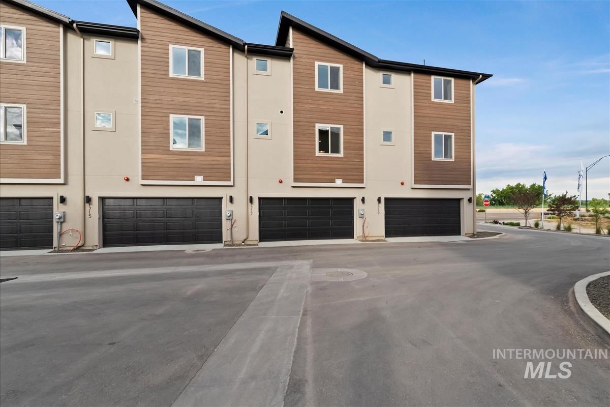 Back of house featuring driveway, stucco siding, and an attached garage