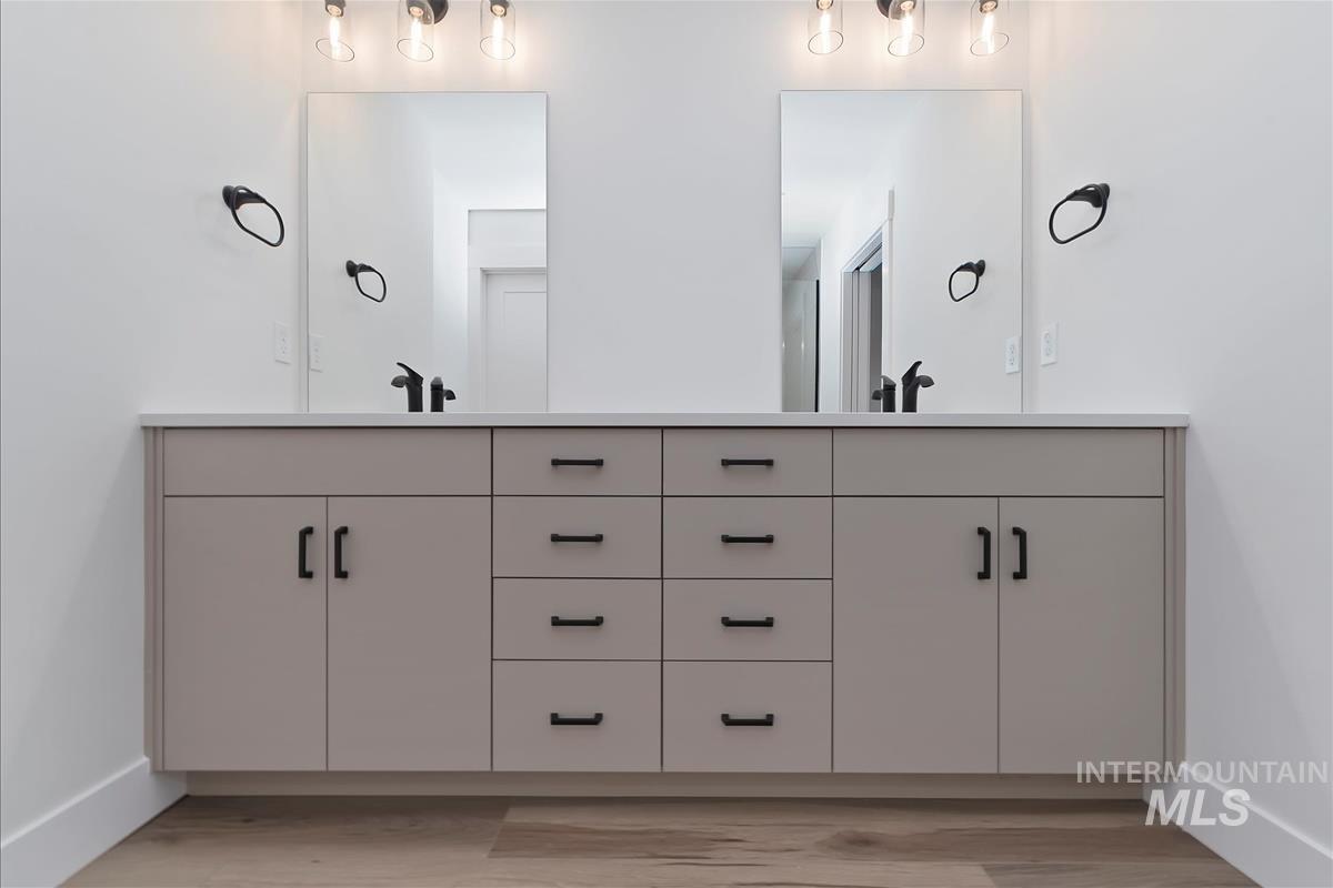 Full bath featuring double vanity and light wood finished floors