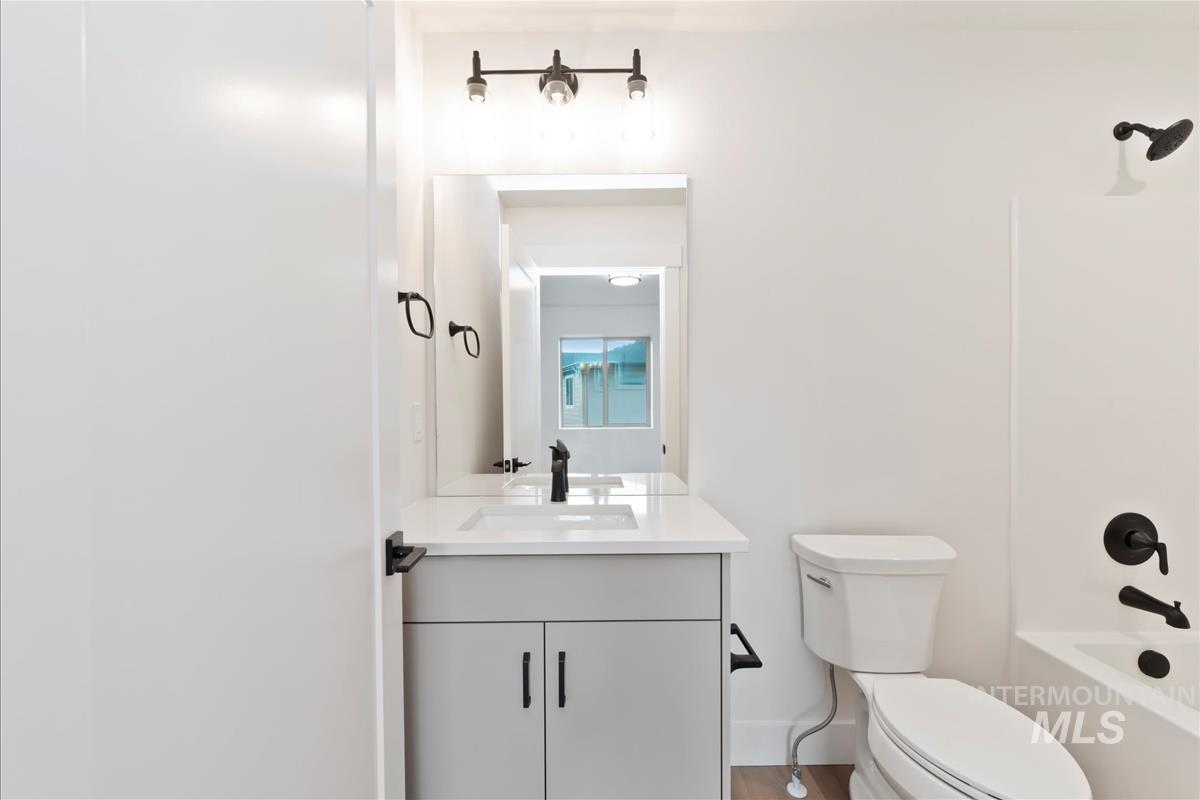 Full bath with vanity, tub / shower combination, and light wood finished floors