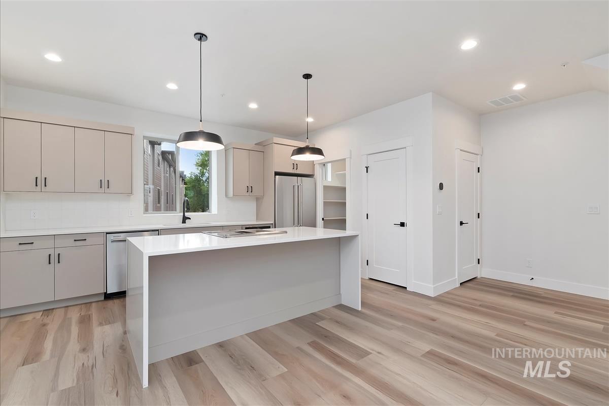 Kitchen with hanging light fixtures, a kitchen island, recessed lighting, stainless steel appliances, and light wood-type flooring