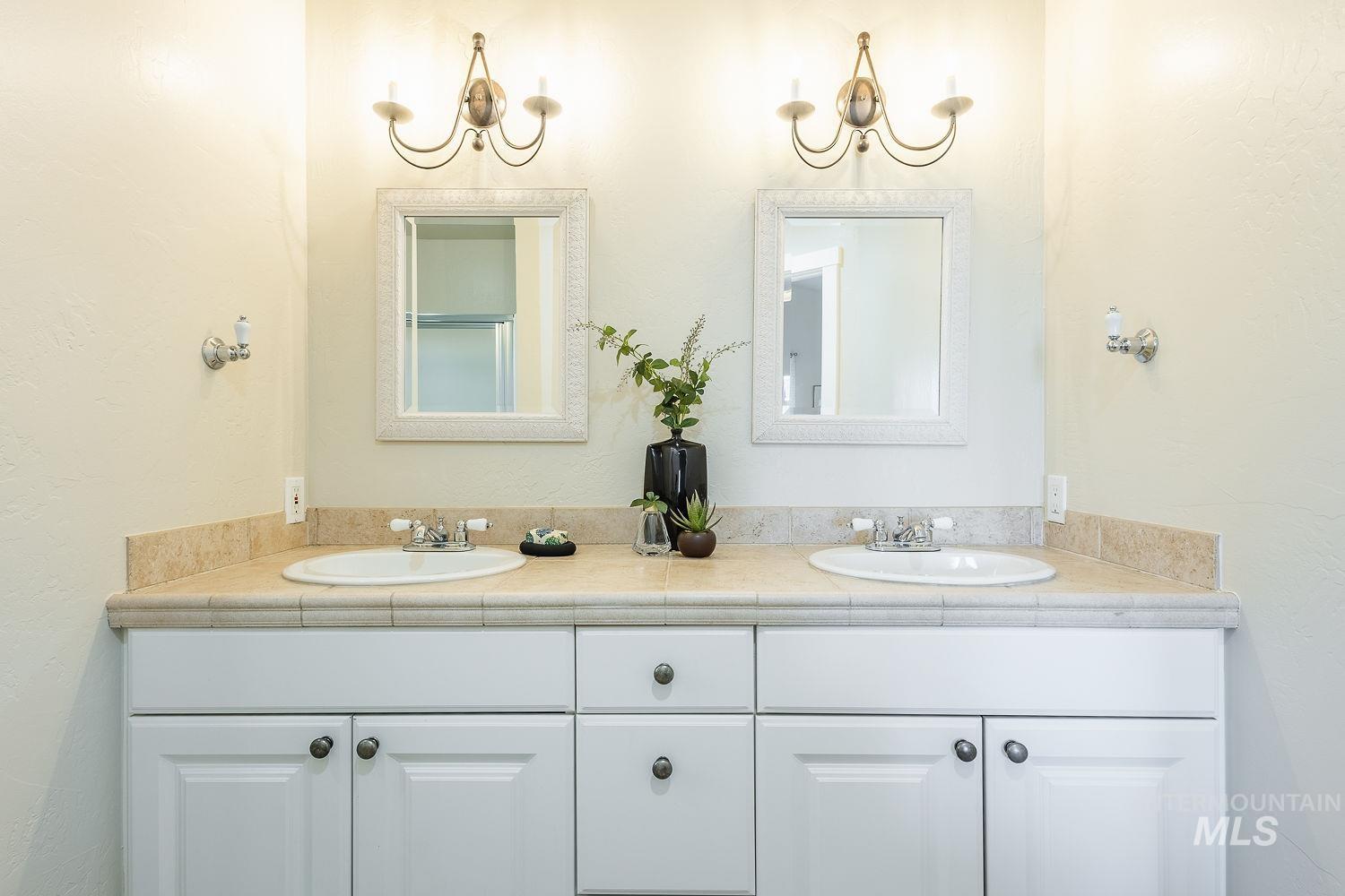 Bathroom with a textured wall, double vanity, and a chandelier