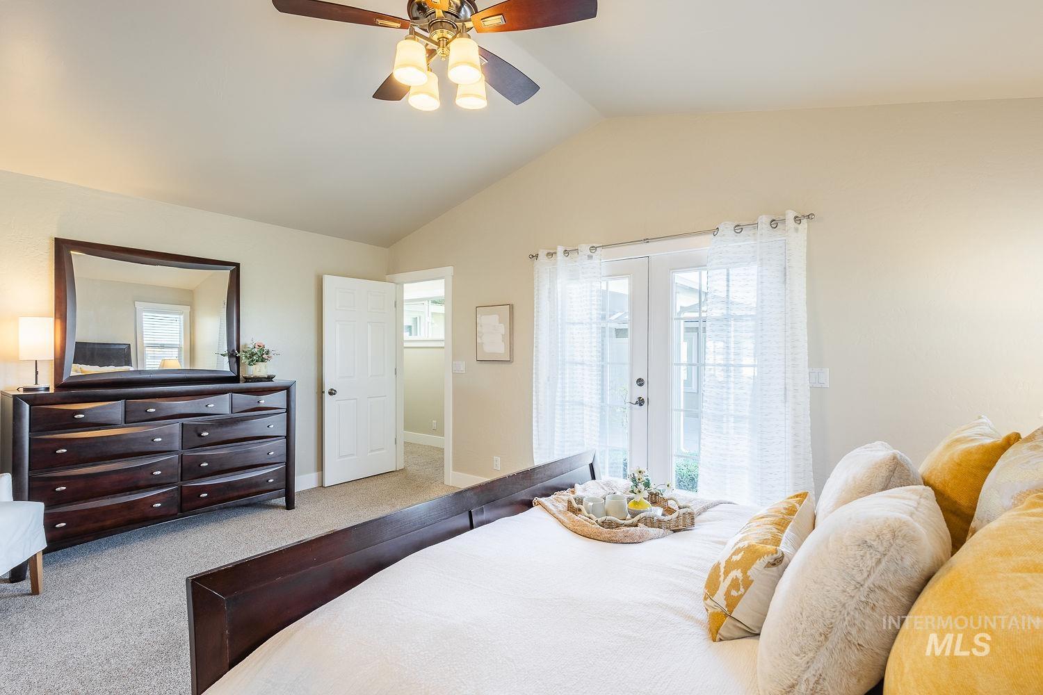 Carpeted bedroom with vaulted ceiling, french doors, ceiling fan, and access to exterior